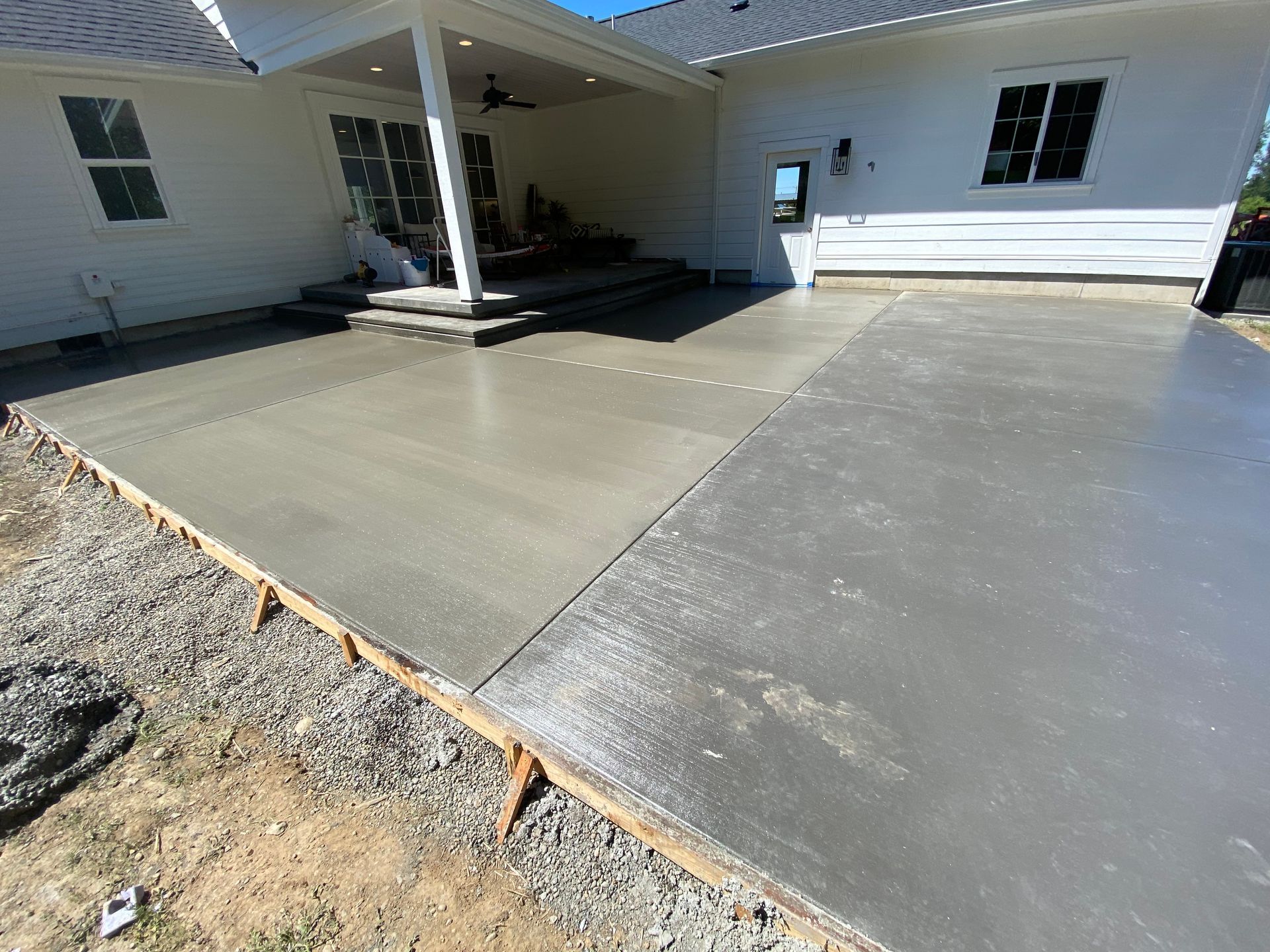 A concrete patio is being built in front of a white house.