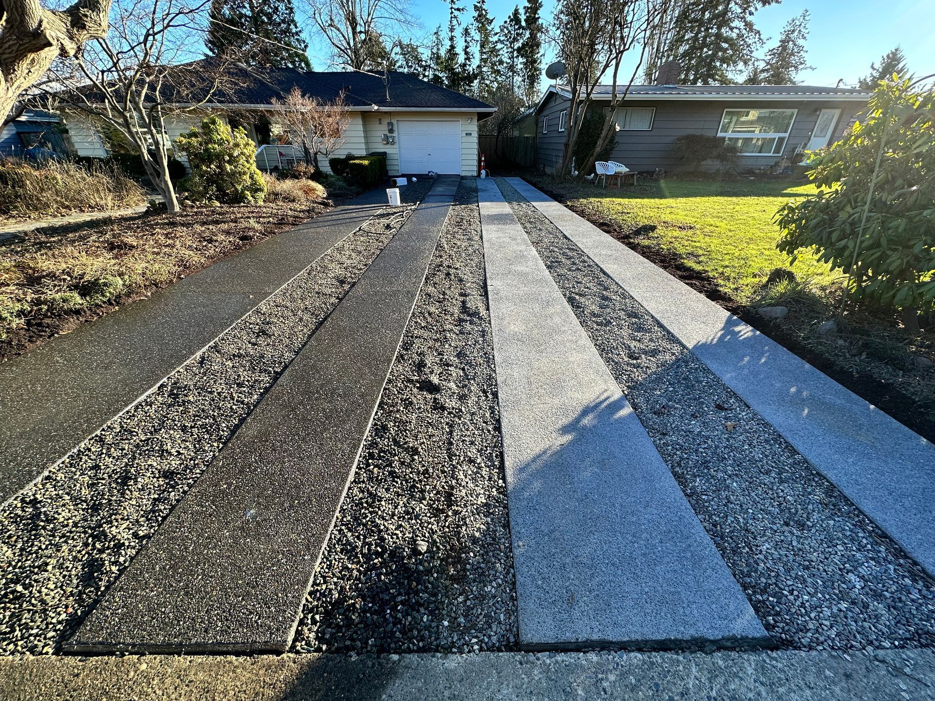 A concrete driveway leading to a house with a striped pattern.