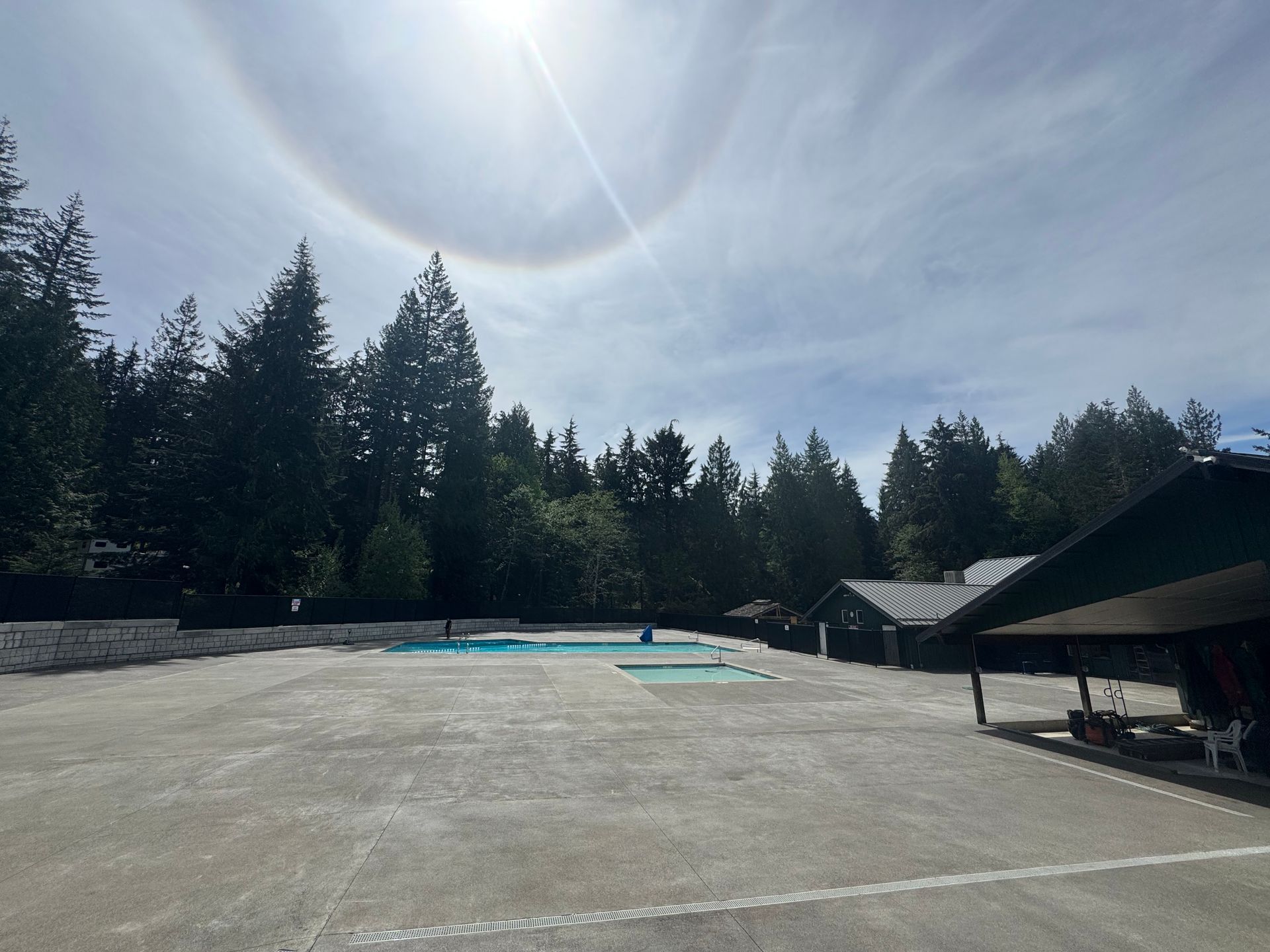 The sun is shining through the clouds over a swimming pool.