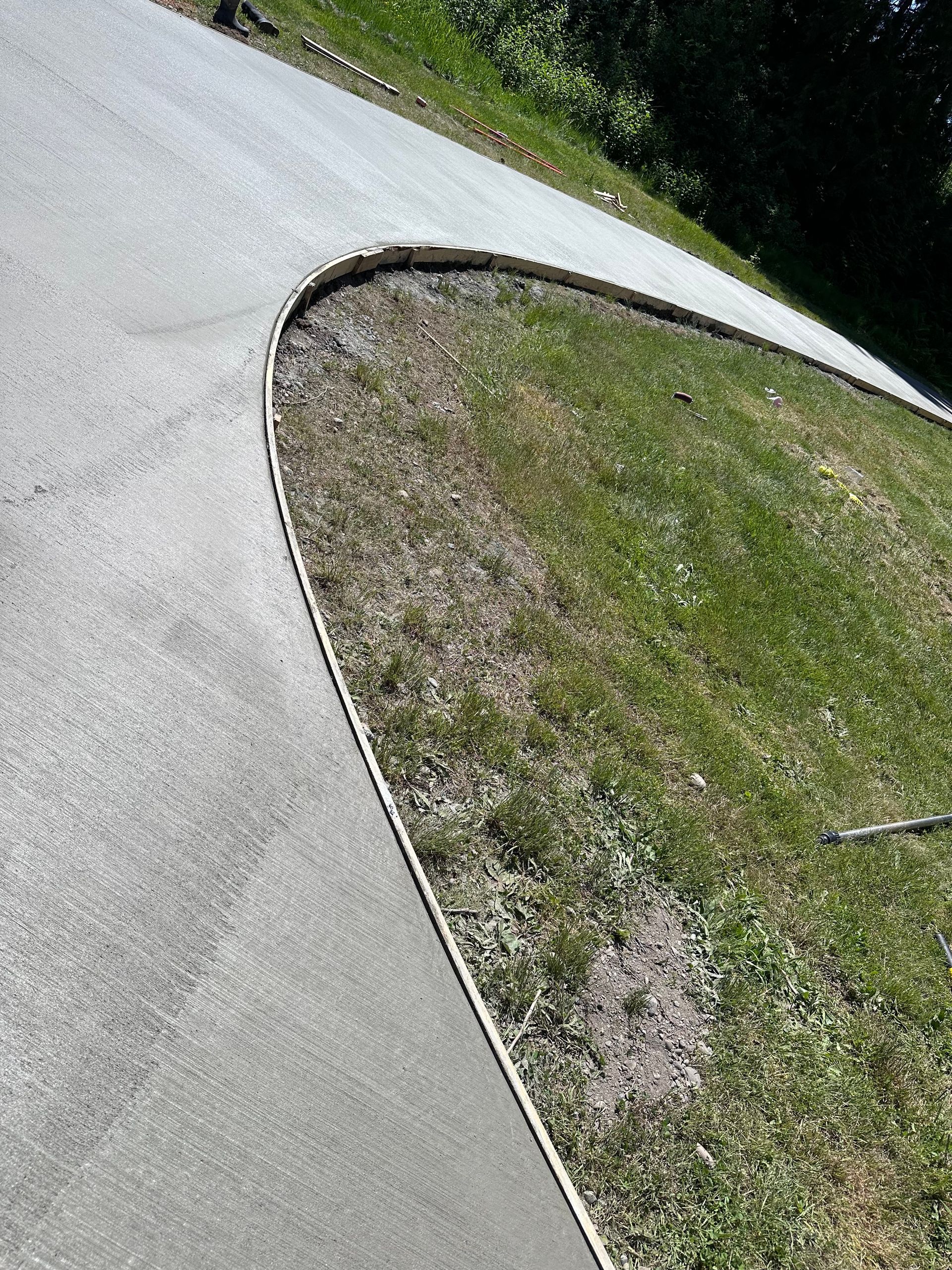A concrete driveway is being built next to a grassy hillside.
