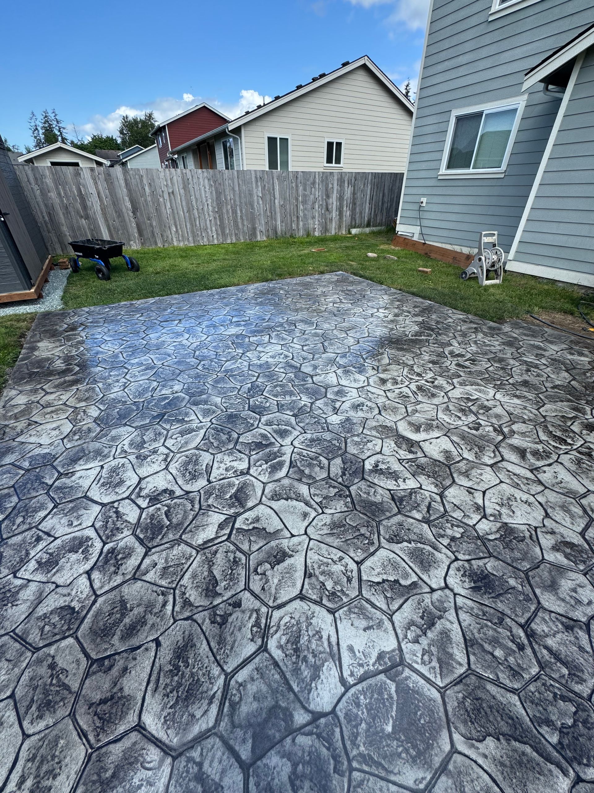 There is a concrete patio in the backyard of a house.