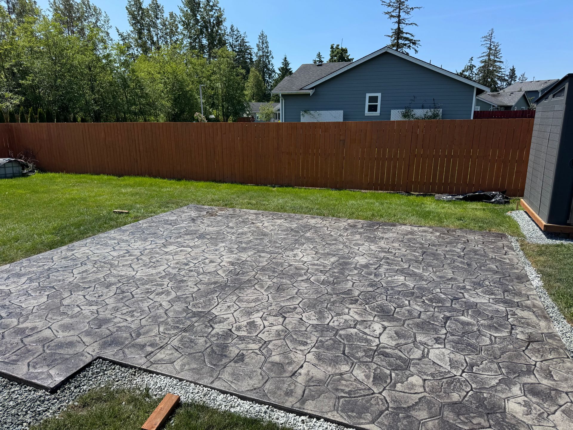 A concrete patio is being built in the backyard of a house.