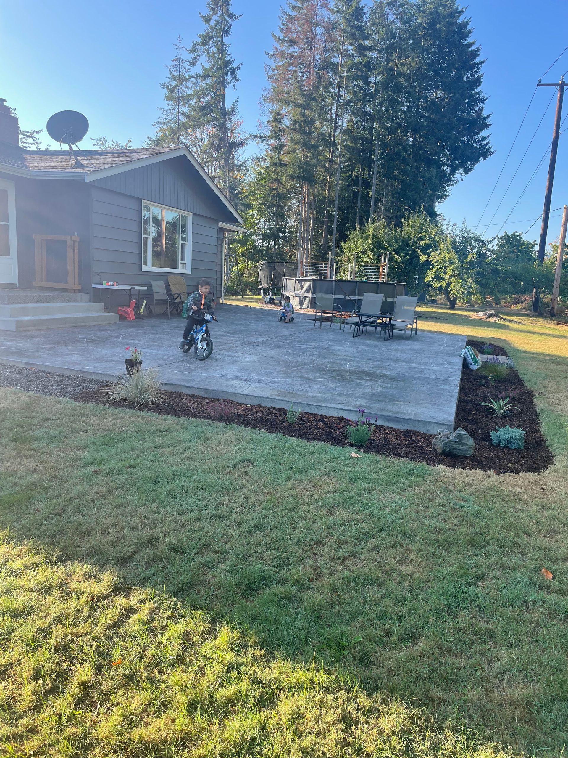 A child is riding a bike on a patio in front of a house.