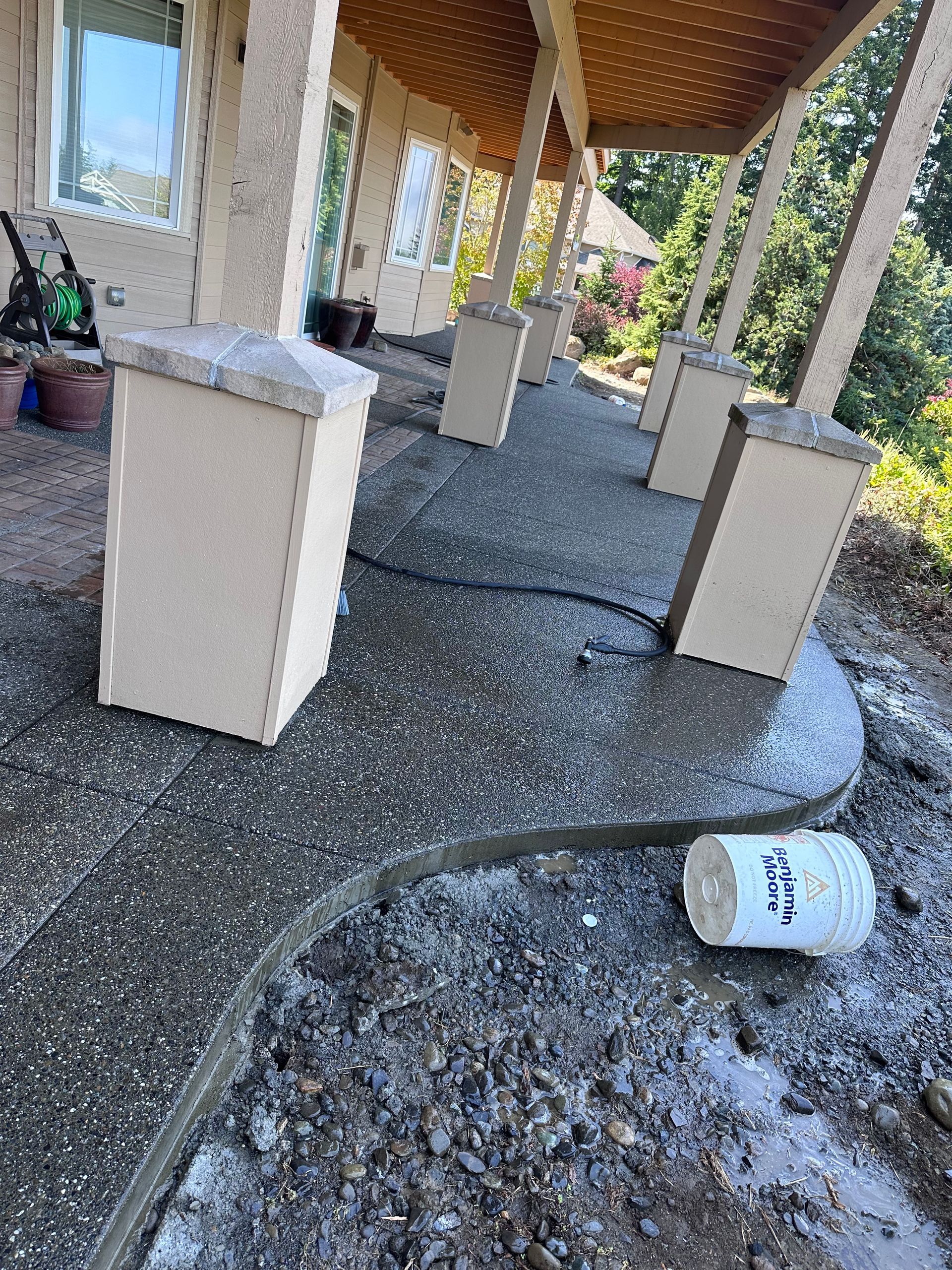 A bottle is laying on the ground under a porch.
