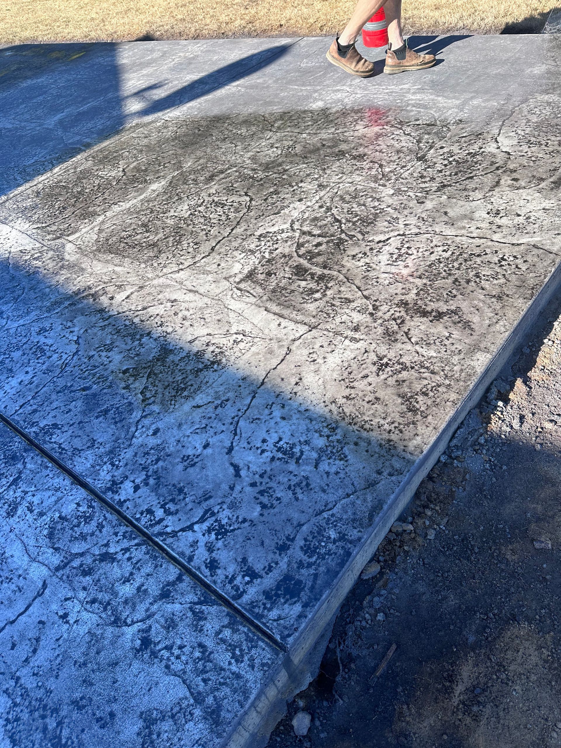 A person is walking on a concrete sidewalk.