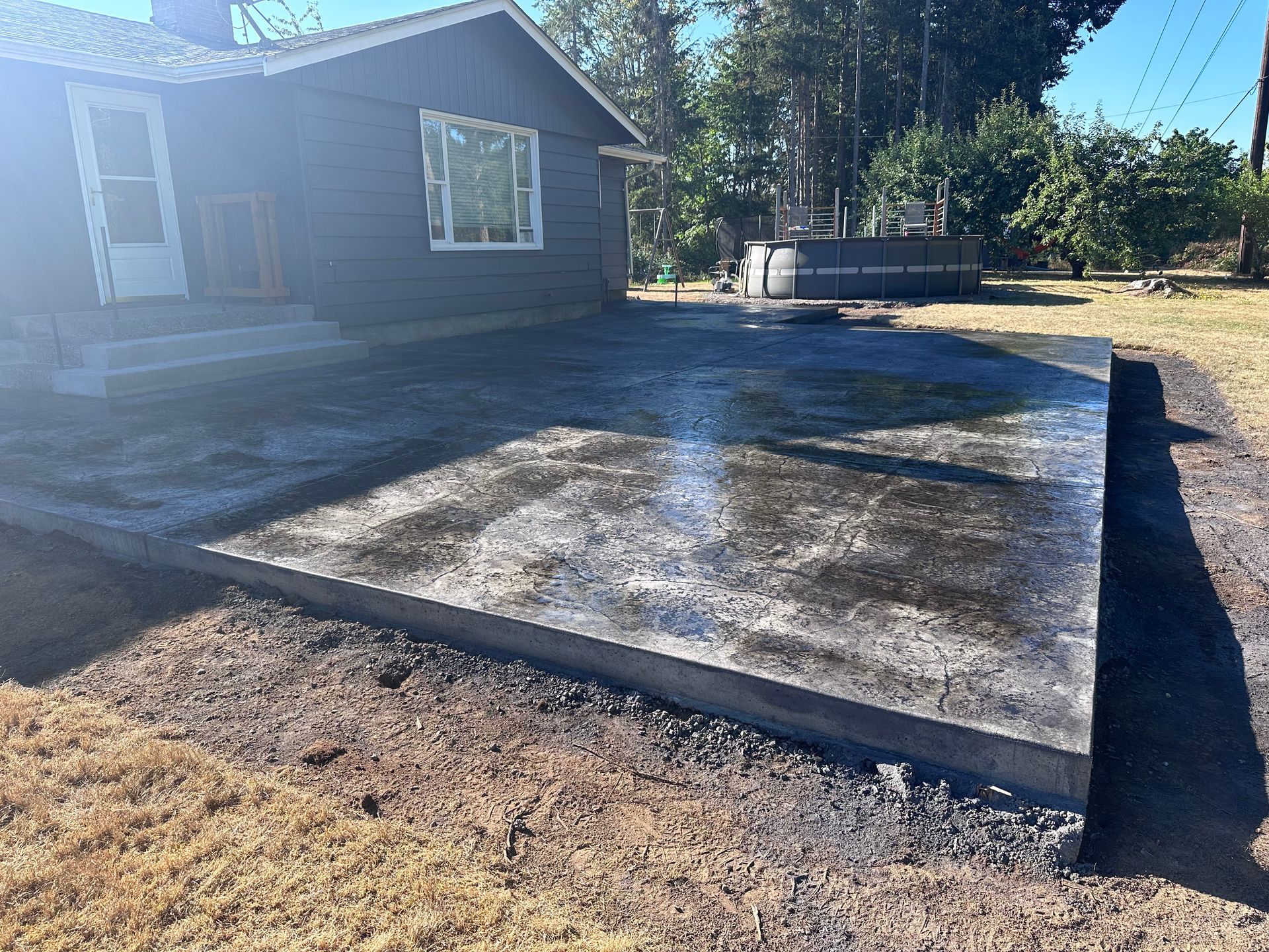 A concrete patio is being built in front of a house.