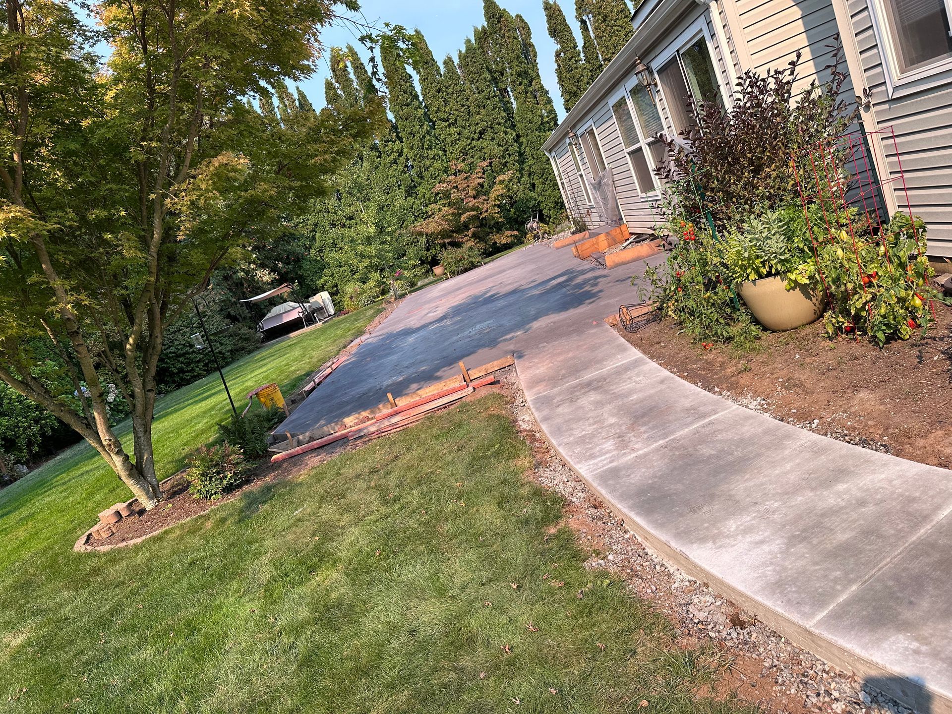 A concrete walkway leading to a house with trees in the background.