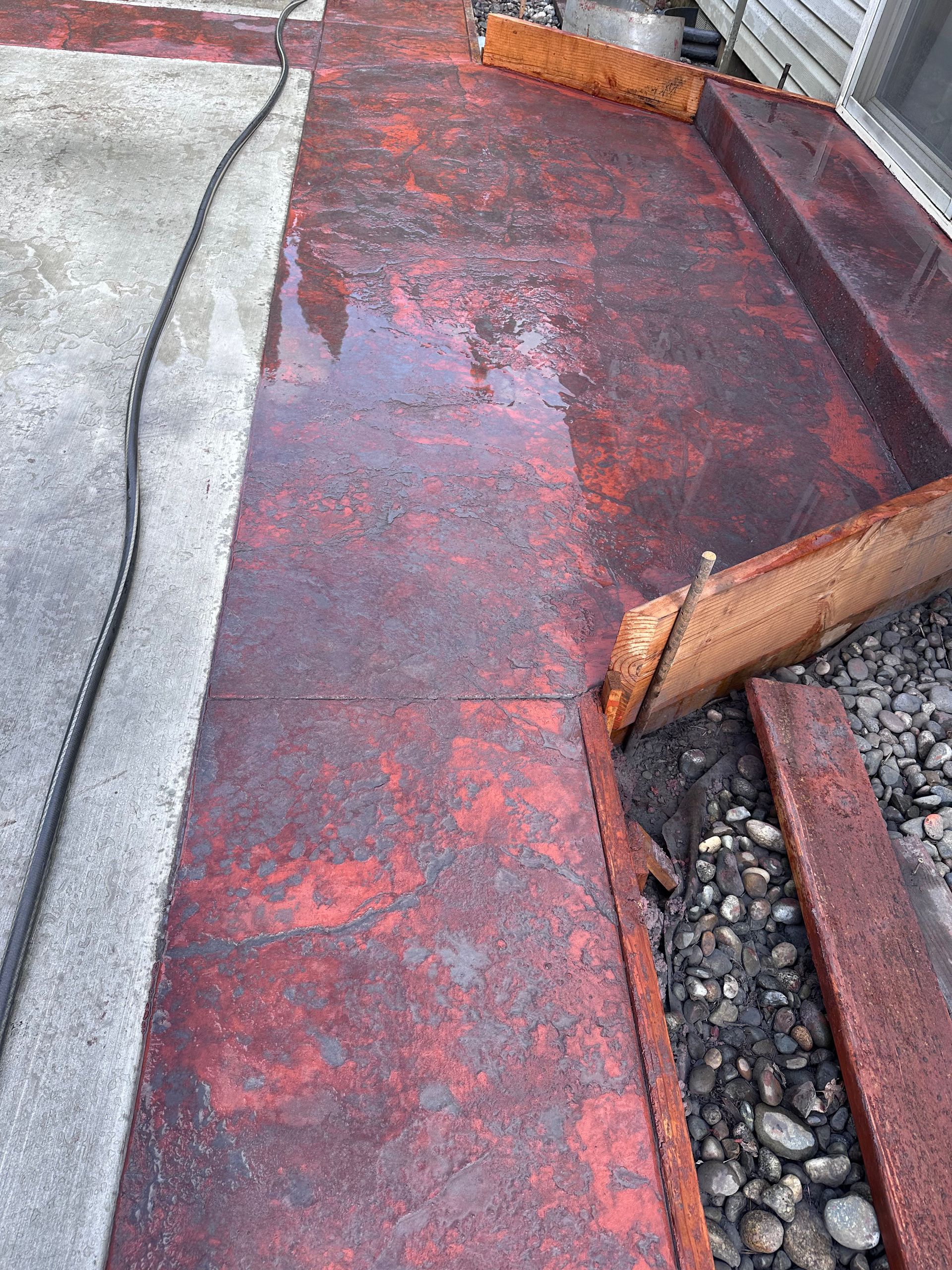 A red concrete walkway with a hose attached to it.