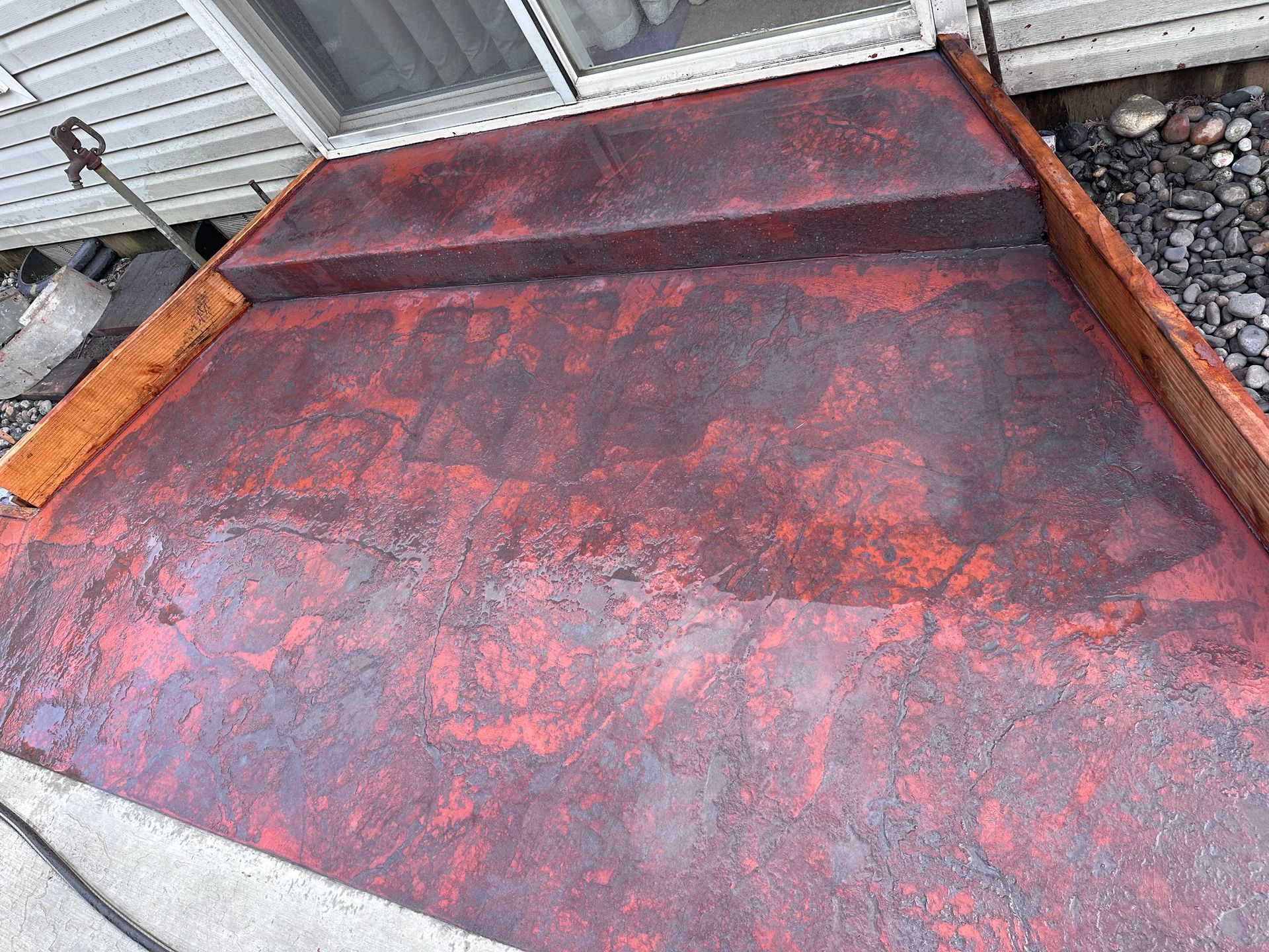 A red concrete walkway with steps leading to a house.