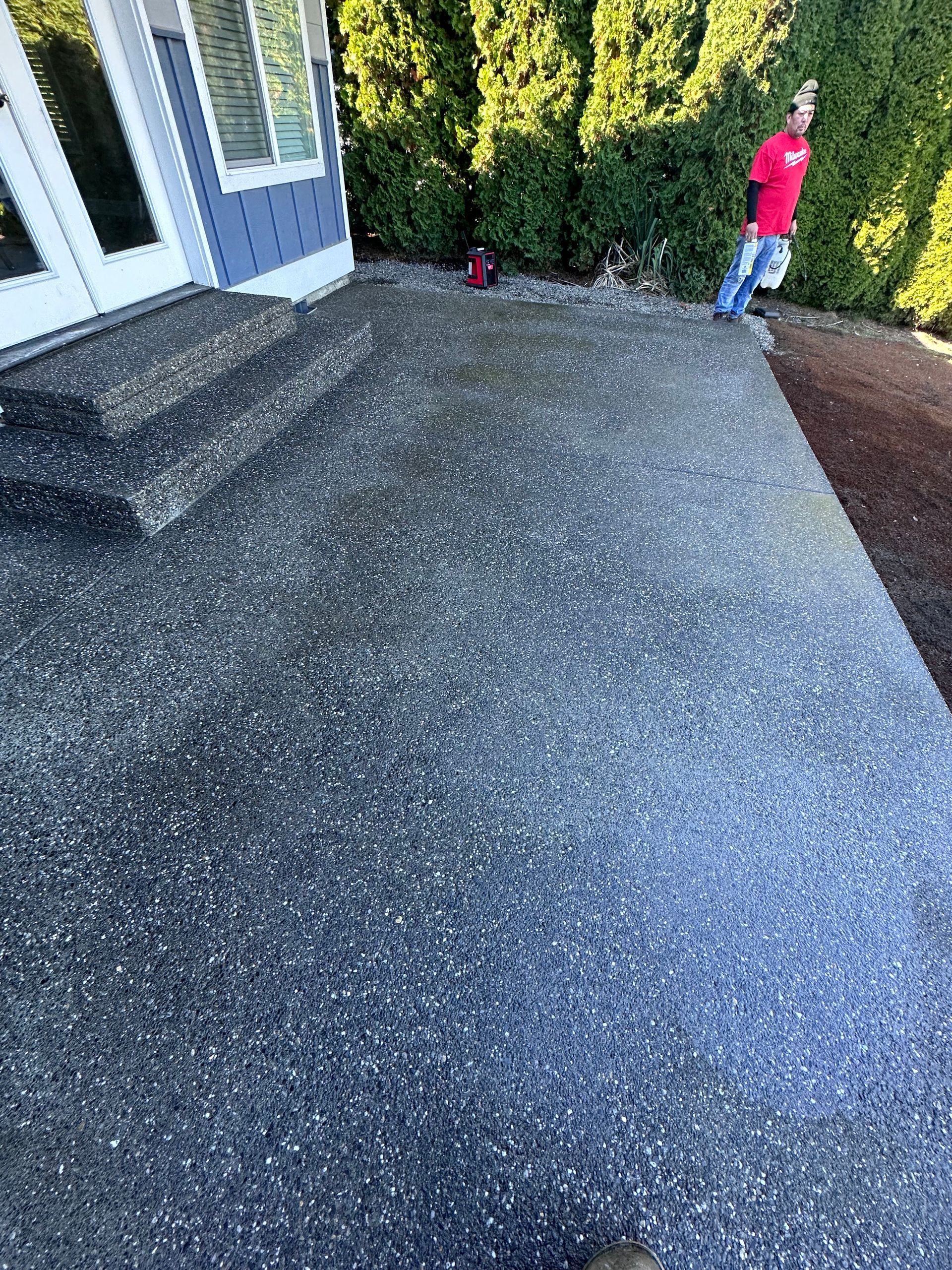 A man is standing on a concrete patio in front of a house.