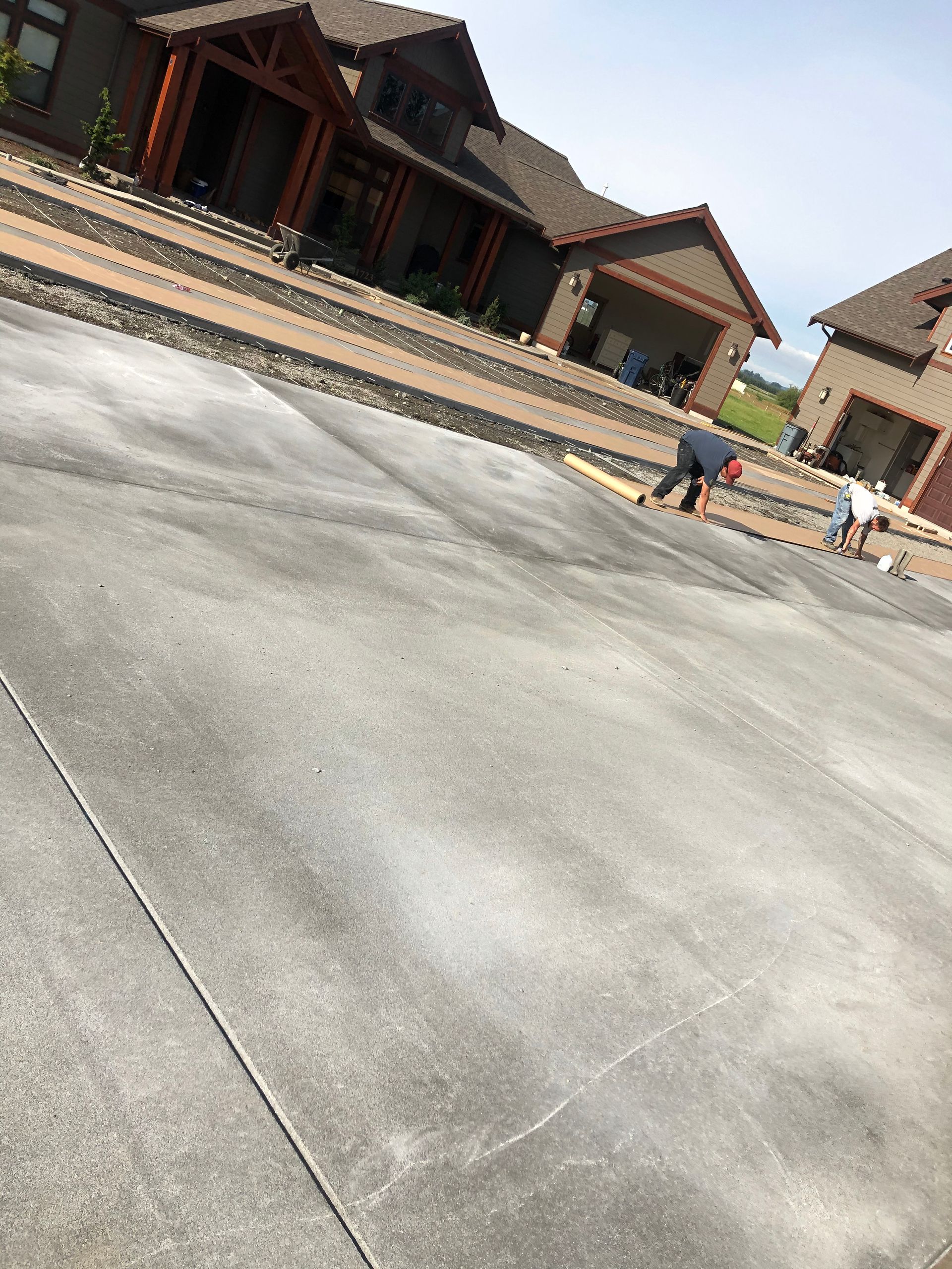 A man is working on a concrete driveway in front of a house.