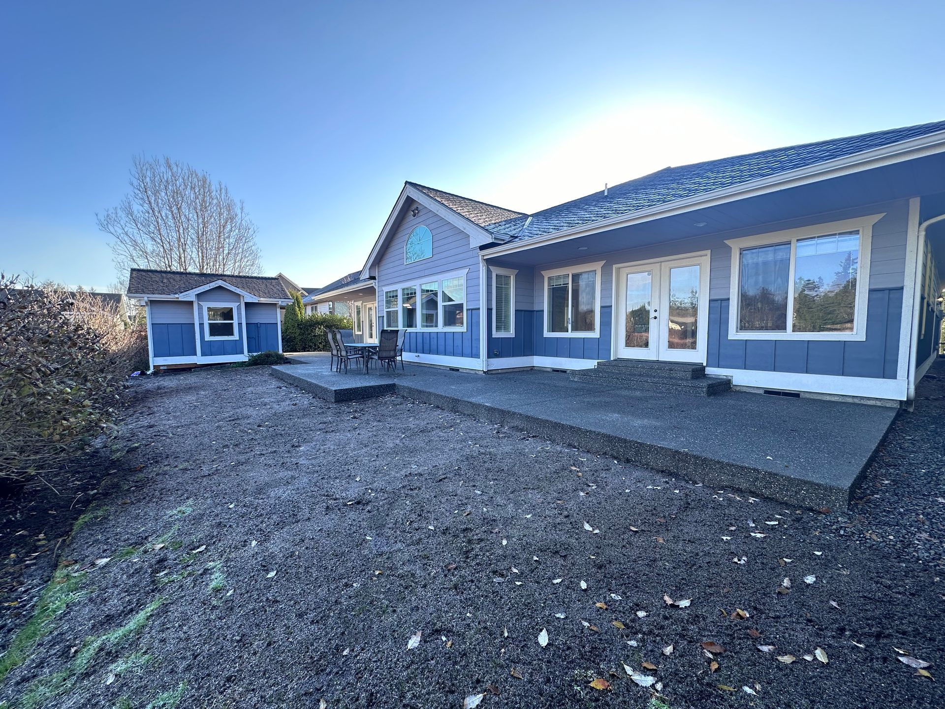 A blue house with a lot of windows and a patio in front of it.