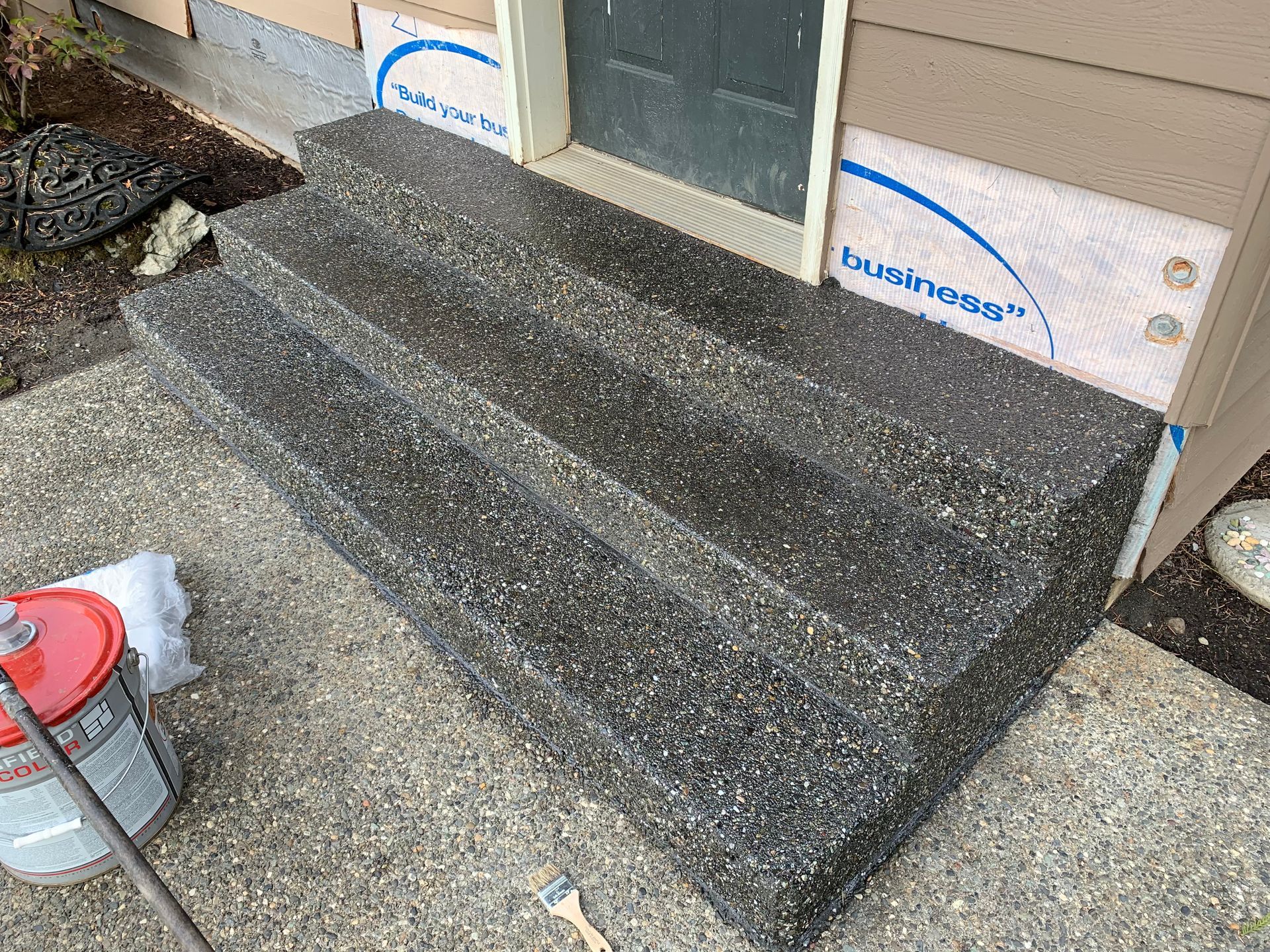 A vacuum cleaner is sitting on the sidewalk next to a set of stairs.