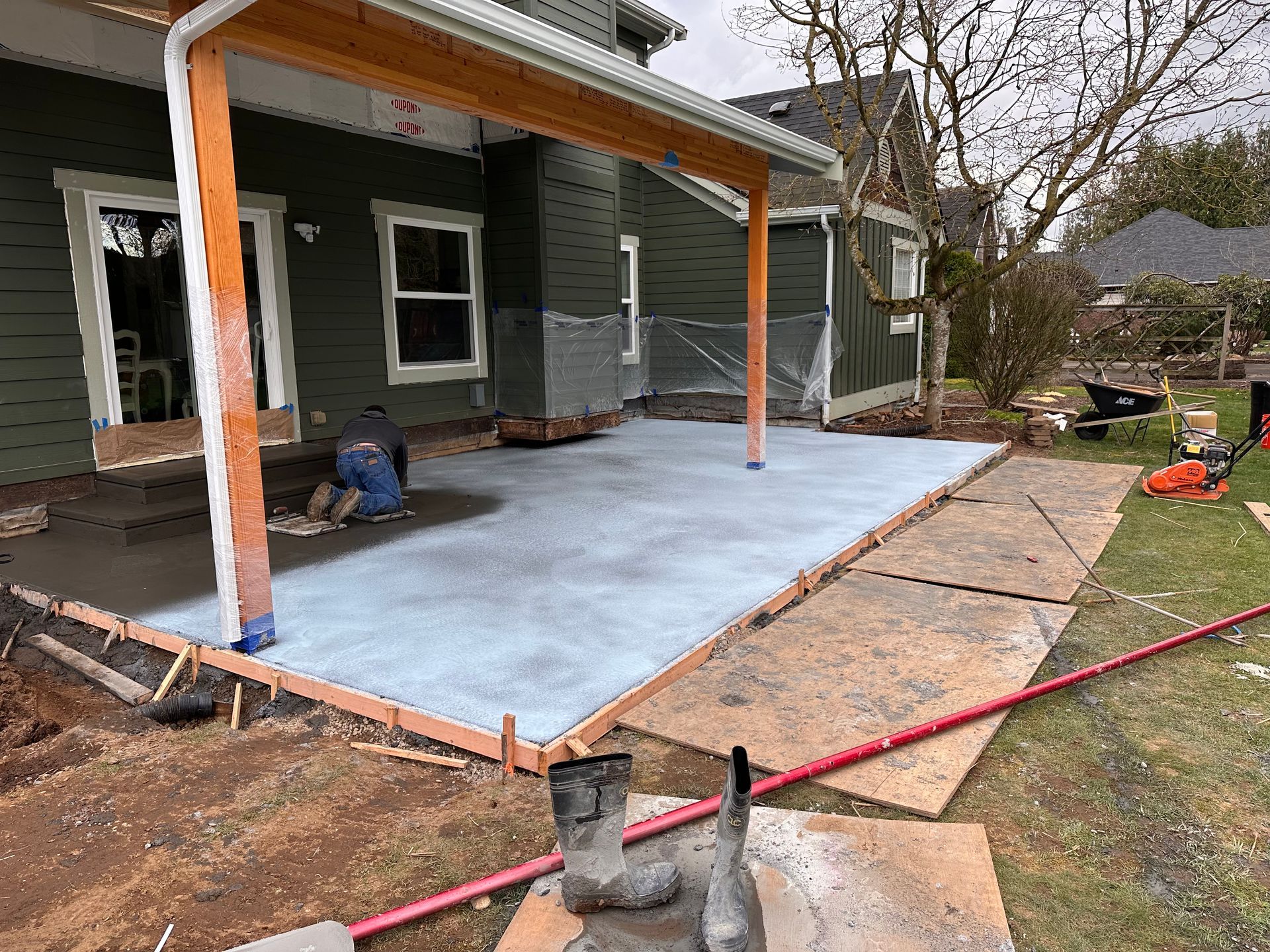 A concrete patio is being built in front of a house.
