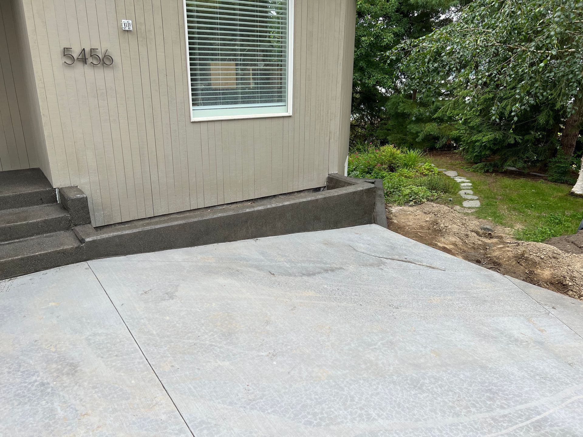 A concrete driveway in front of a house with the address 5456