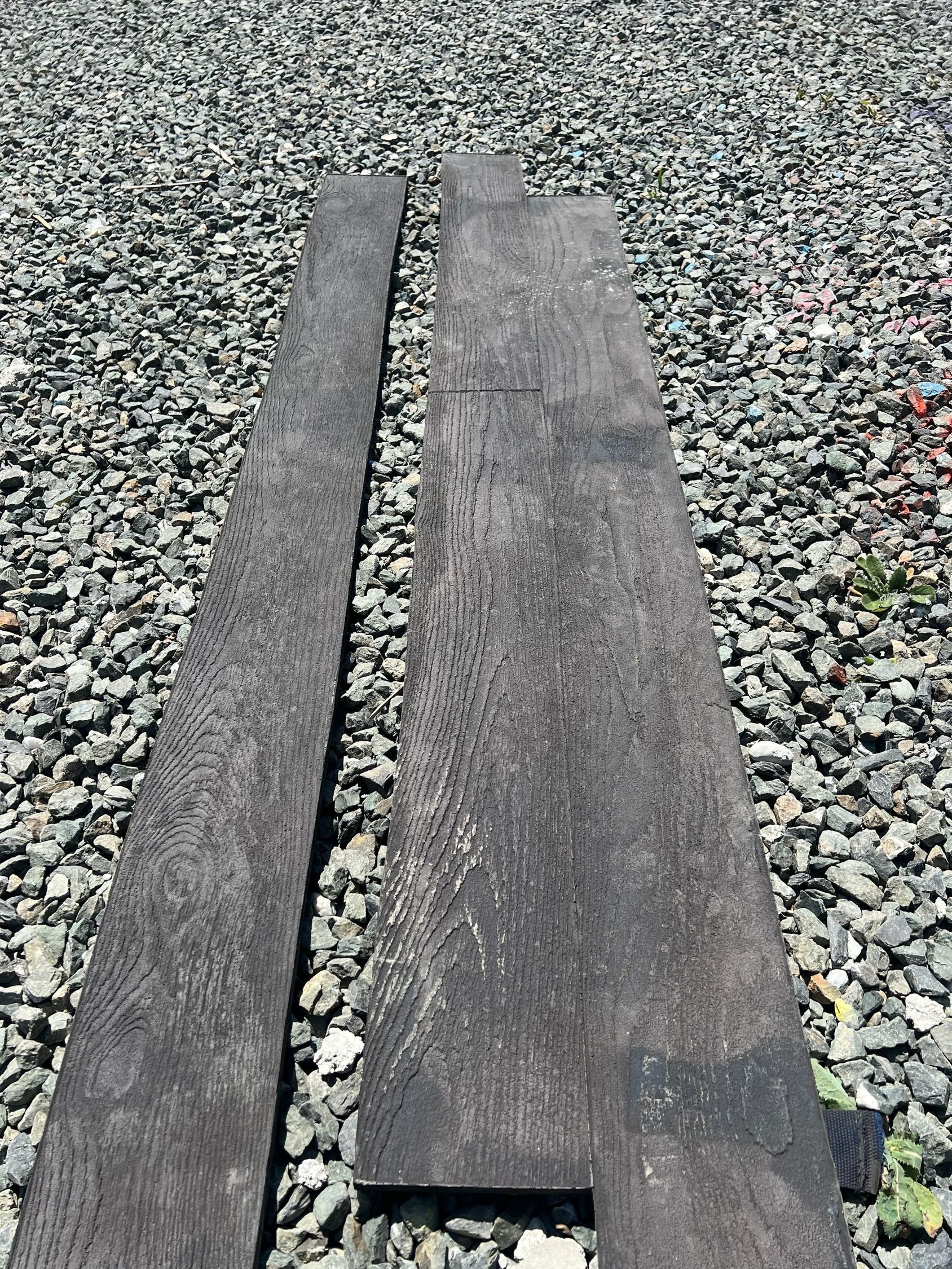 Two wooden boards are sitting on top of a pile of gravel.