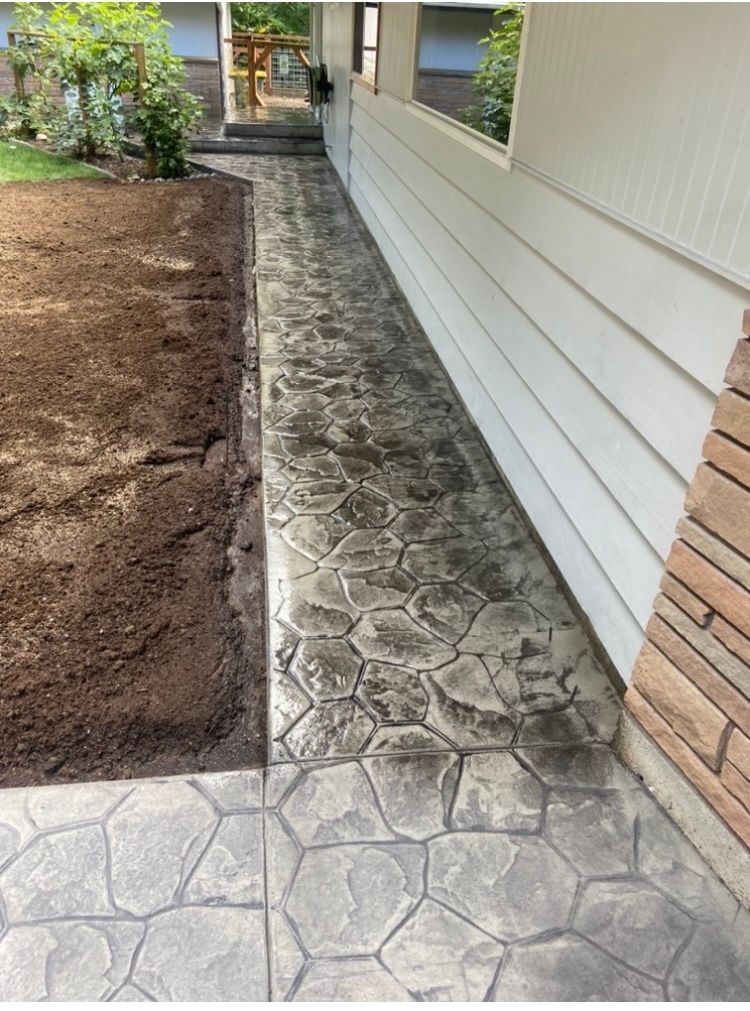 A concrete walkway leading to the side of a house.