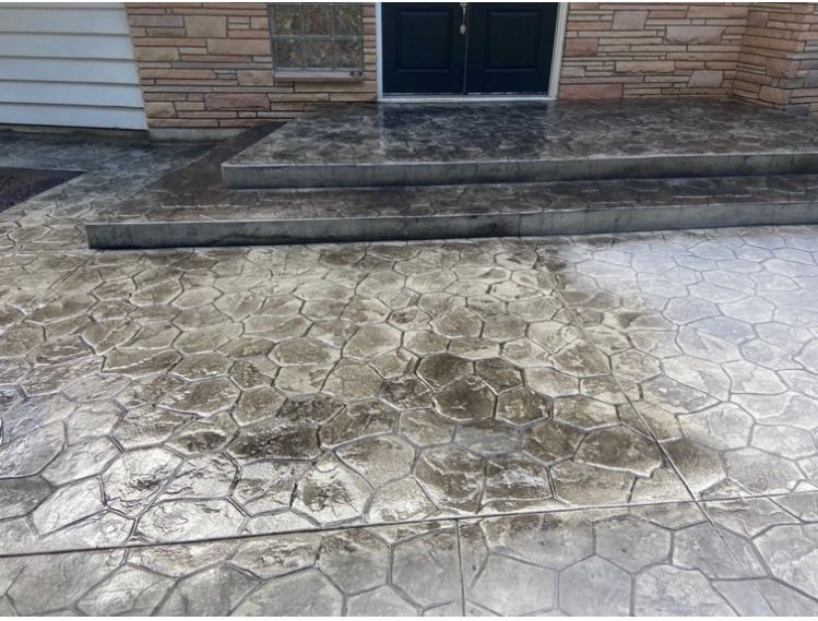 A dirty concrete walkway with stairs in front of a house.