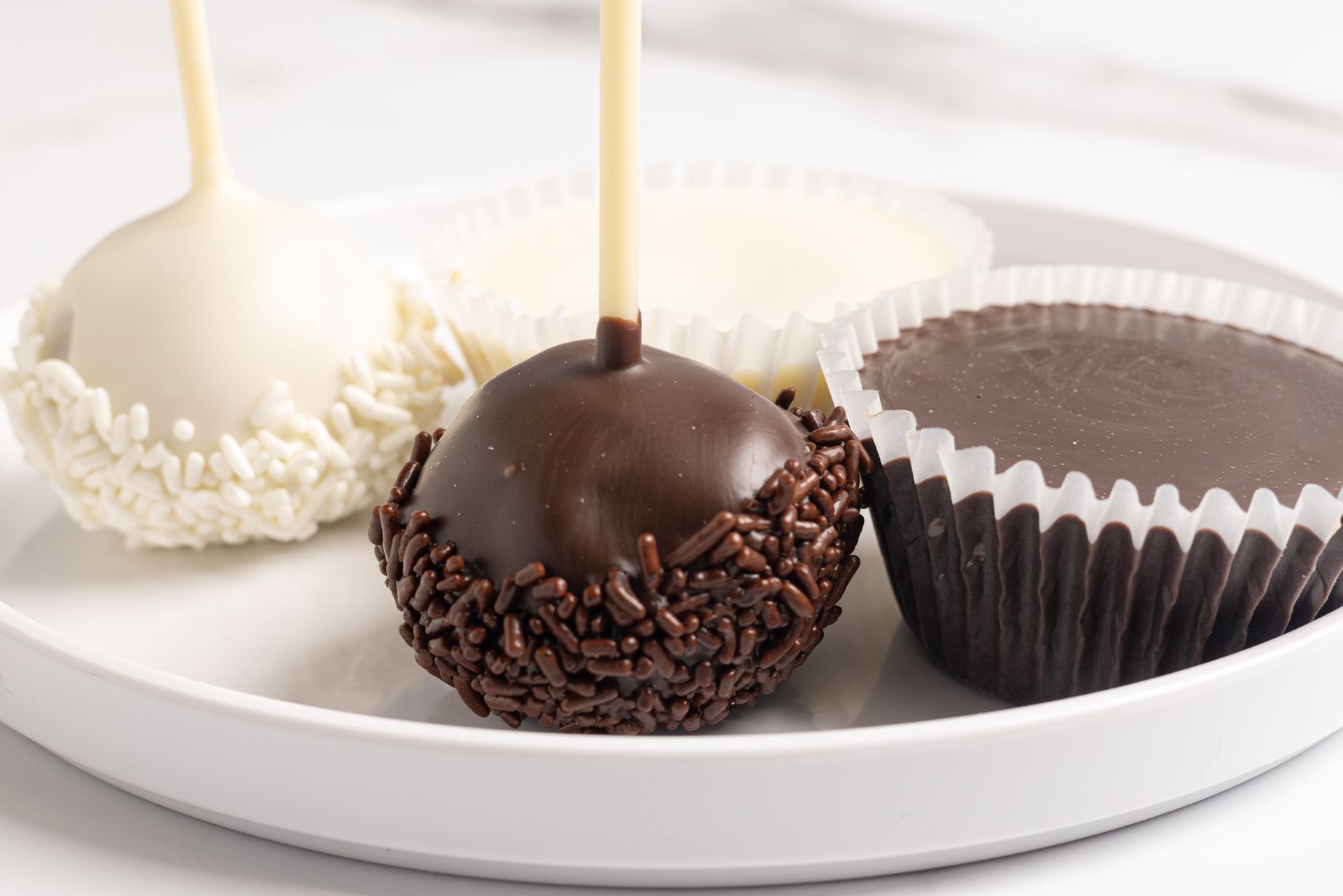 Two cake pops and two cupcakes, one of each as vanilla and one in chocolate