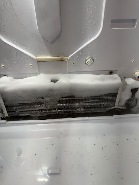 A close up of the inside of a refrigerator with ice coming out of it.