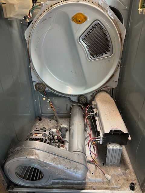 The inside of a dirty dryer with the door open.