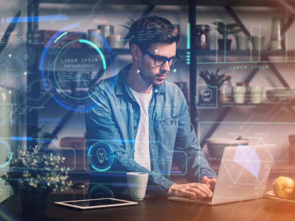 Un hombre con gafas trabaja con una computadora portátil en una cocina, con superposiciones digitales que representan el análisis de datos.