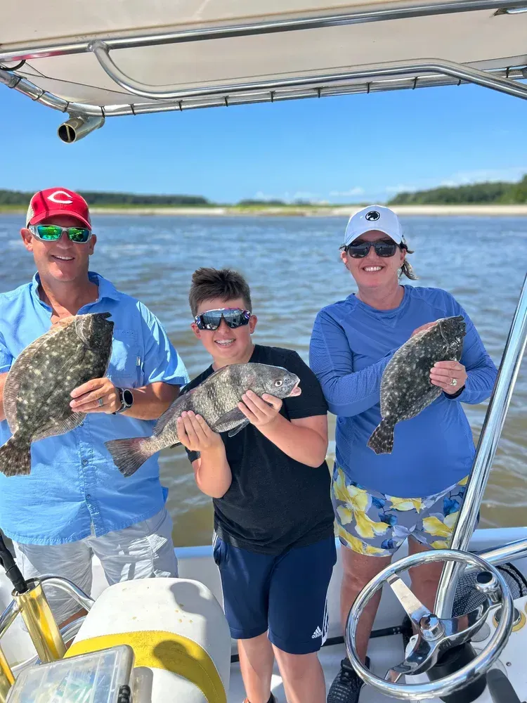 Family on a boat holding up their fish catch. Sunny day on the water.