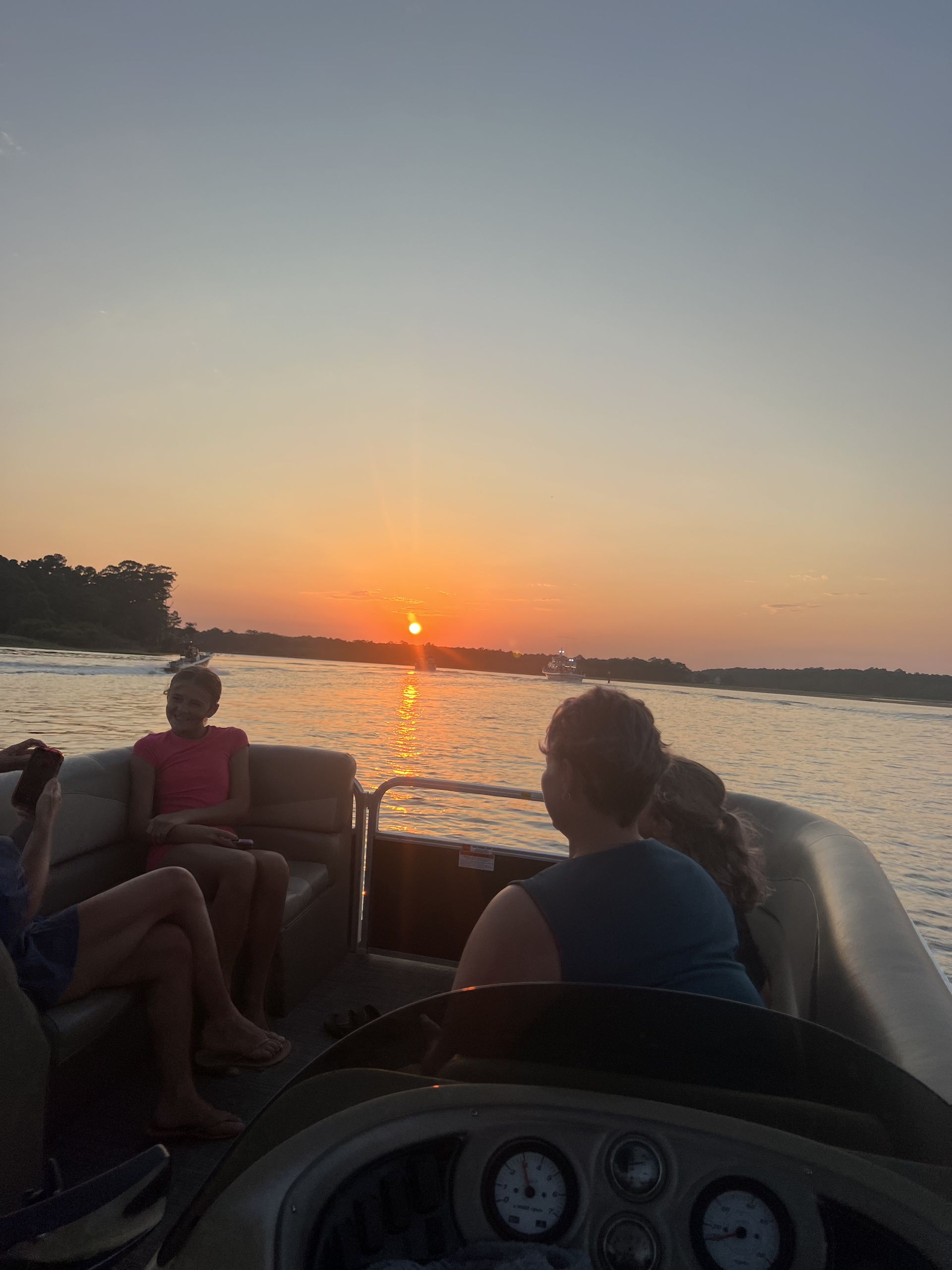 Sunset over ocean, orange and pink sky reflects on water.