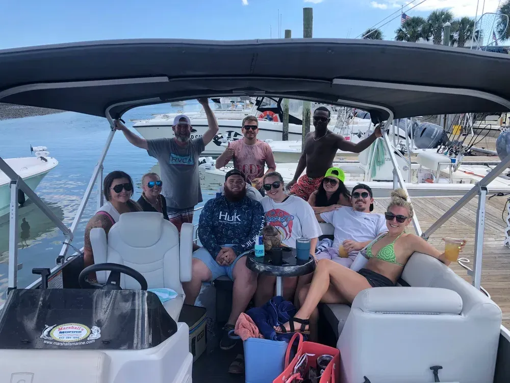 Group of people on a boat. Some are smiling. The sky is visible.
