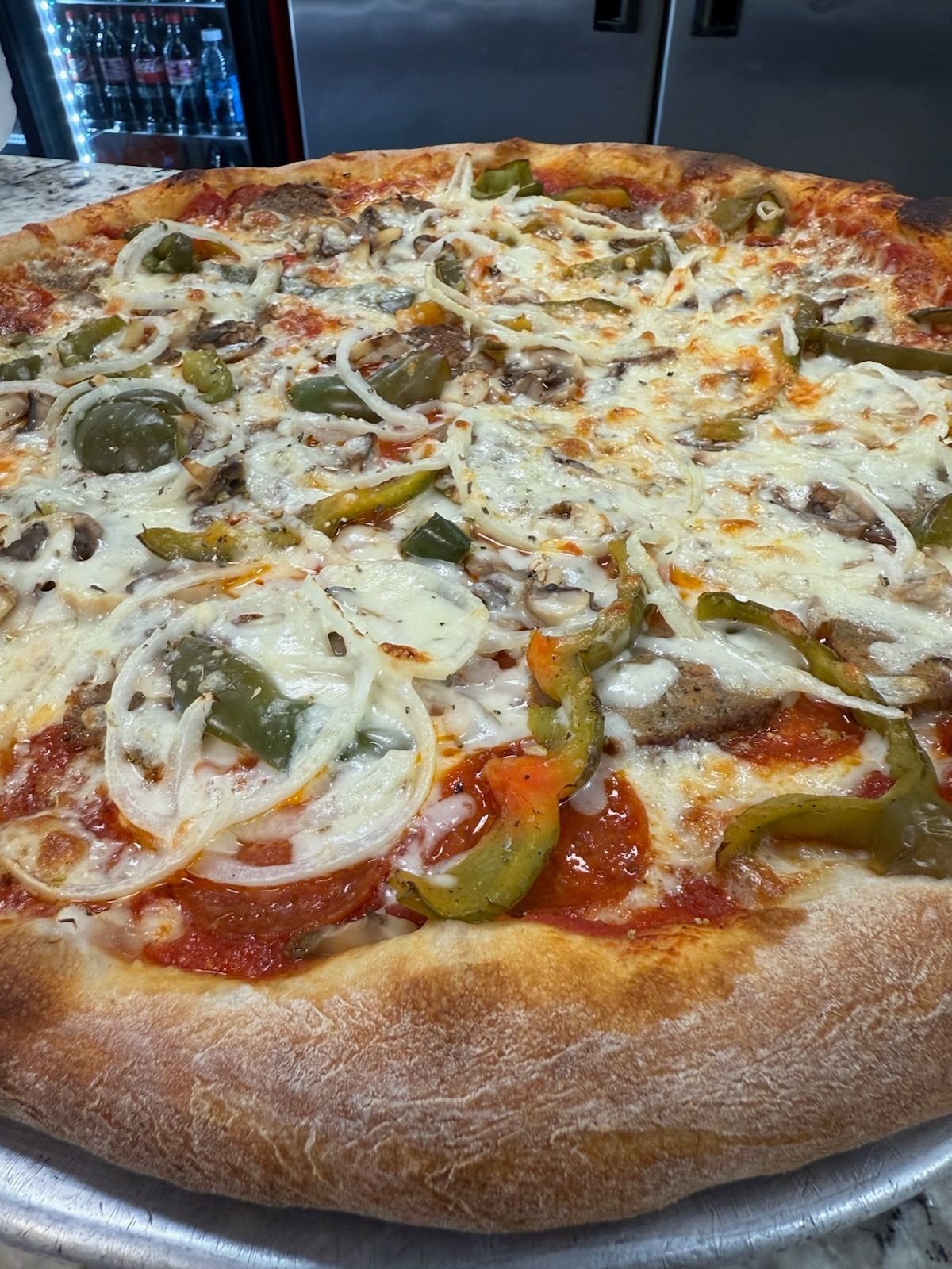 Cheese and green pepper pizza on a metal tray, with melted cheese and browned crust