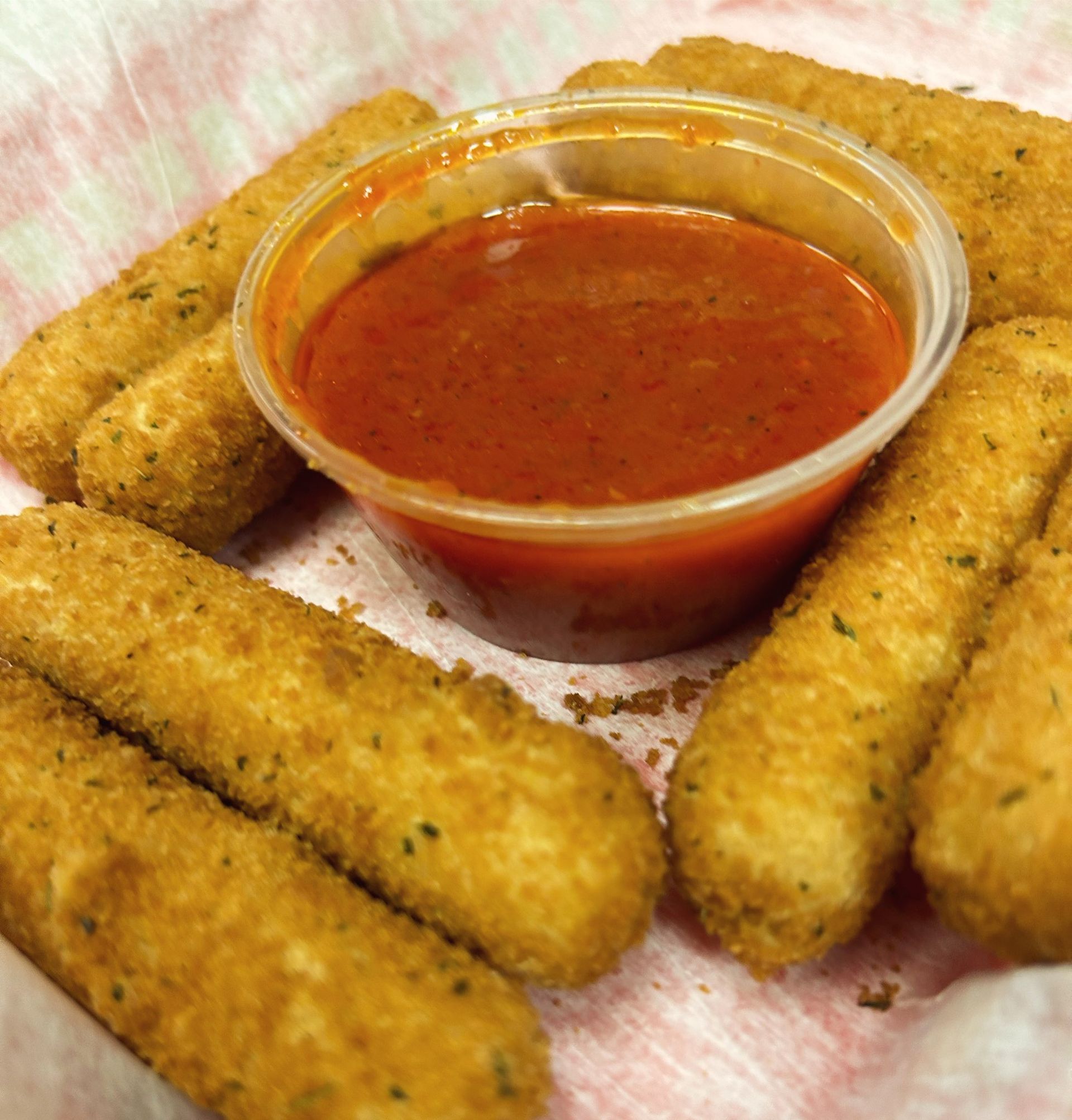 Breaded mozzarella sticks with marinara dipping sauce on a plate