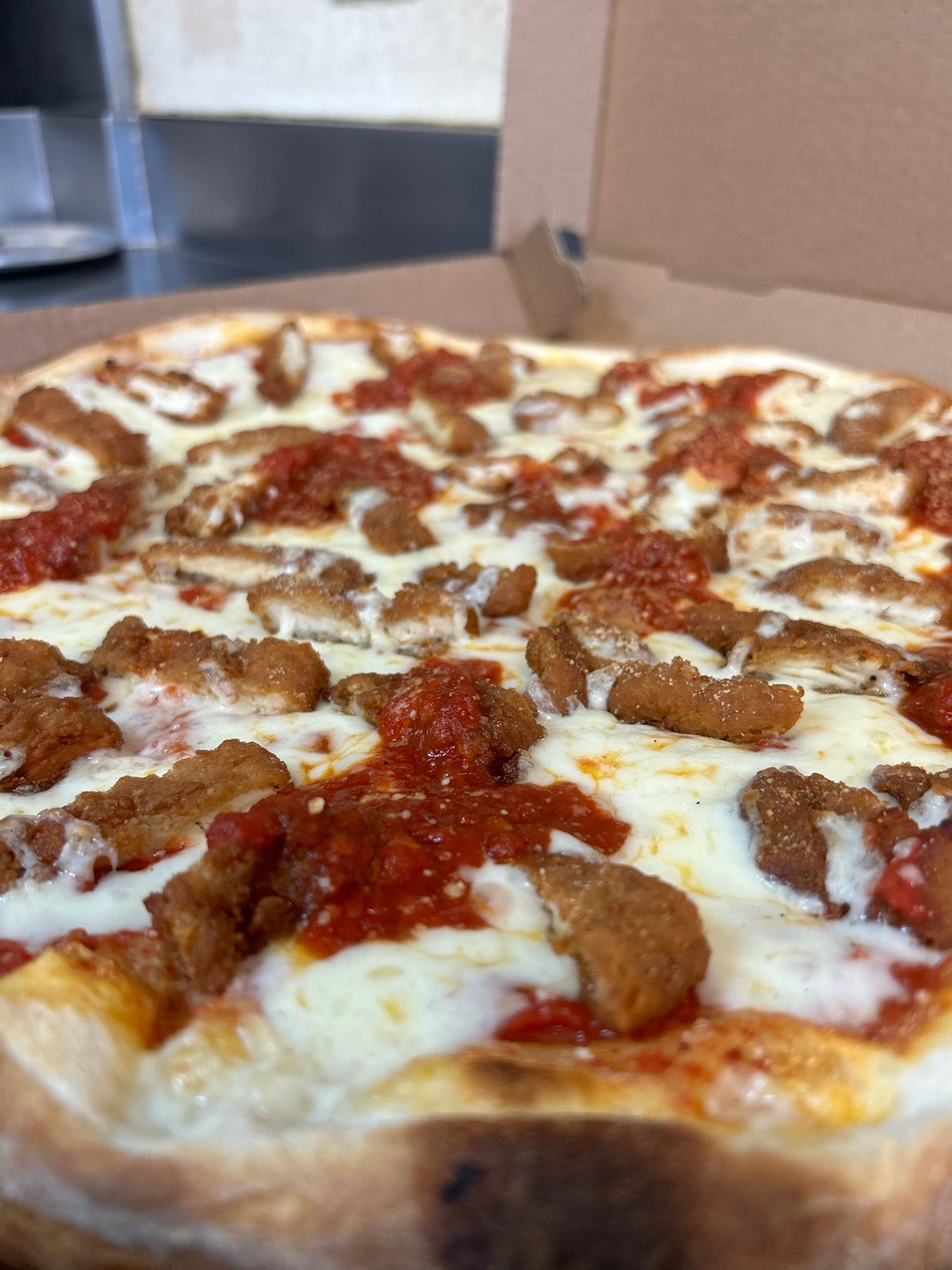 Close-up of a pepperoni and sausage pizza in a cardboard box