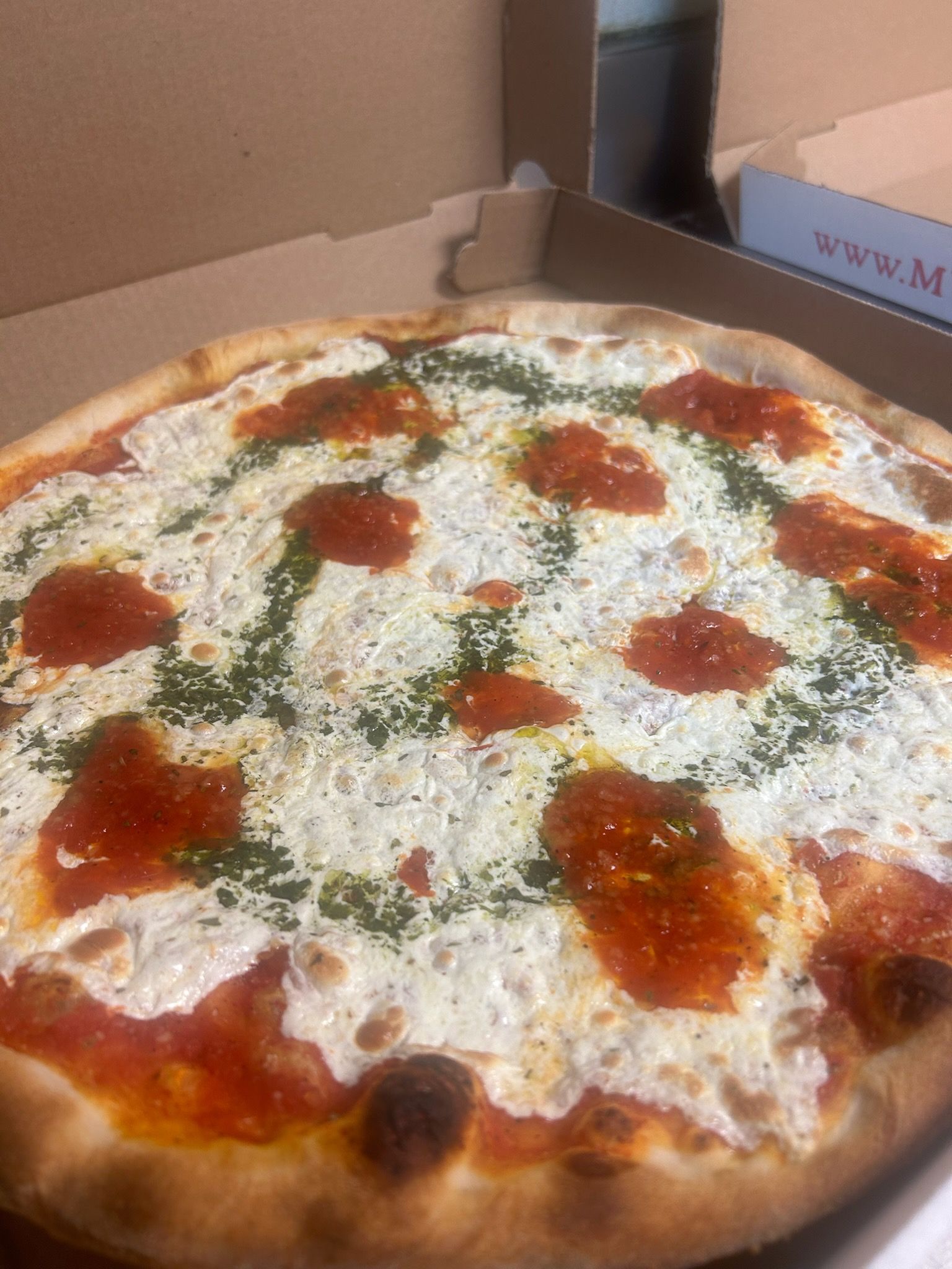 Deep-dish pizza with melted cheese, herbs, and red sauce in a box.