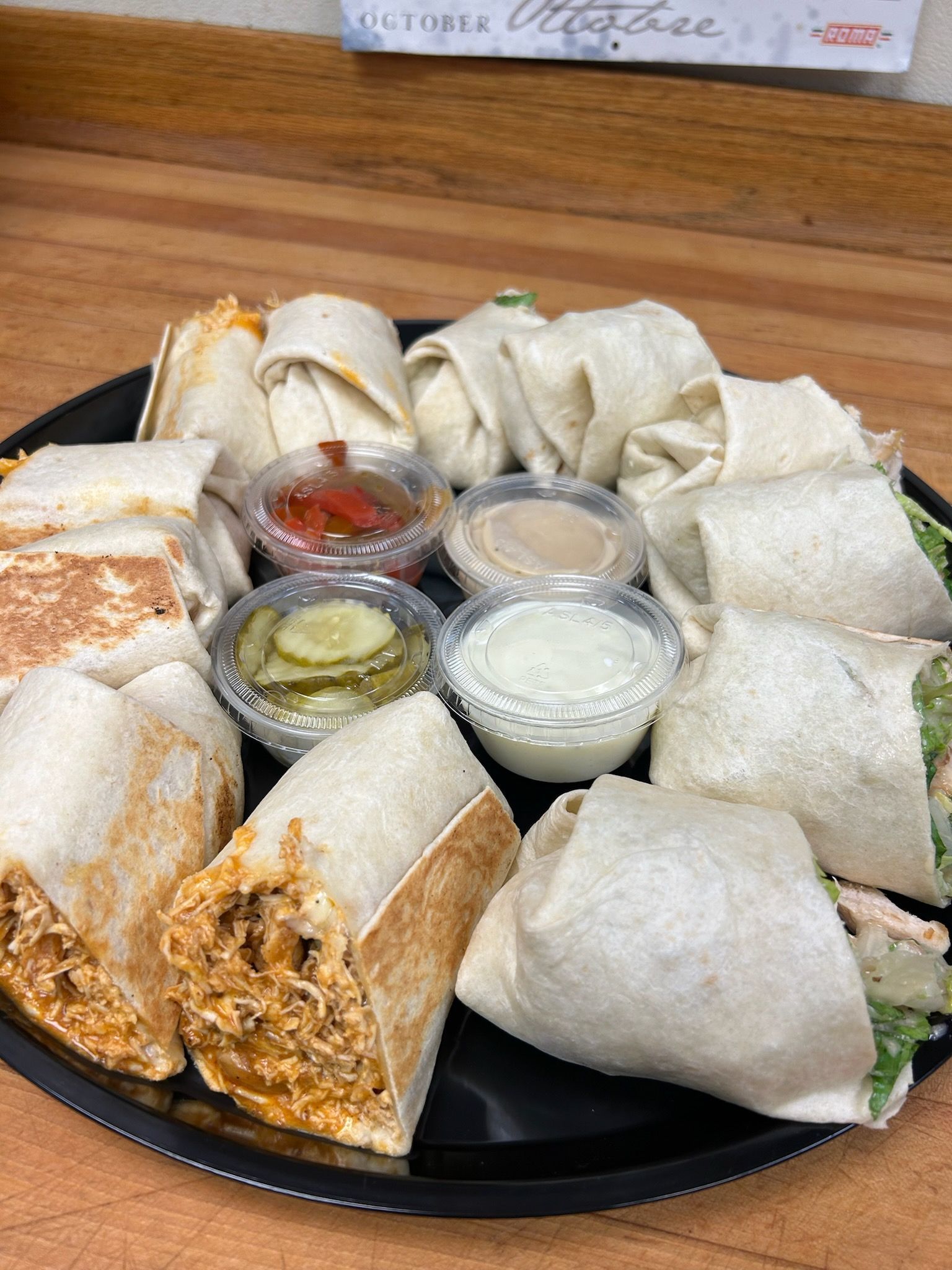 Plate of rolled crepes or dosa with three dipping sauces on a wooden table