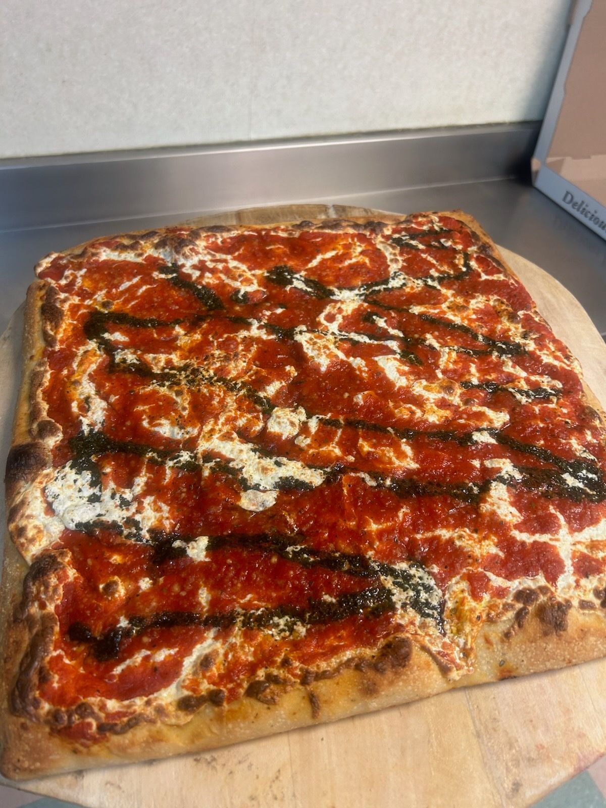 Rectangular baked pizza with red sauce and melted cheese on a cutting board