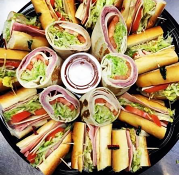 Platter of assorted sandwich wraps arranged in a circle around a dipping sauce