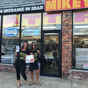 two women are standing in front of a mattress store .