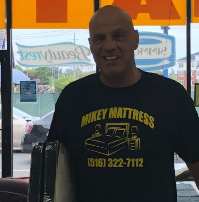 a man wearing a black shirt that says mikey mattress