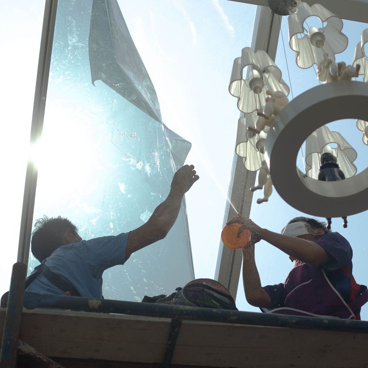 two men are working on a large glass window