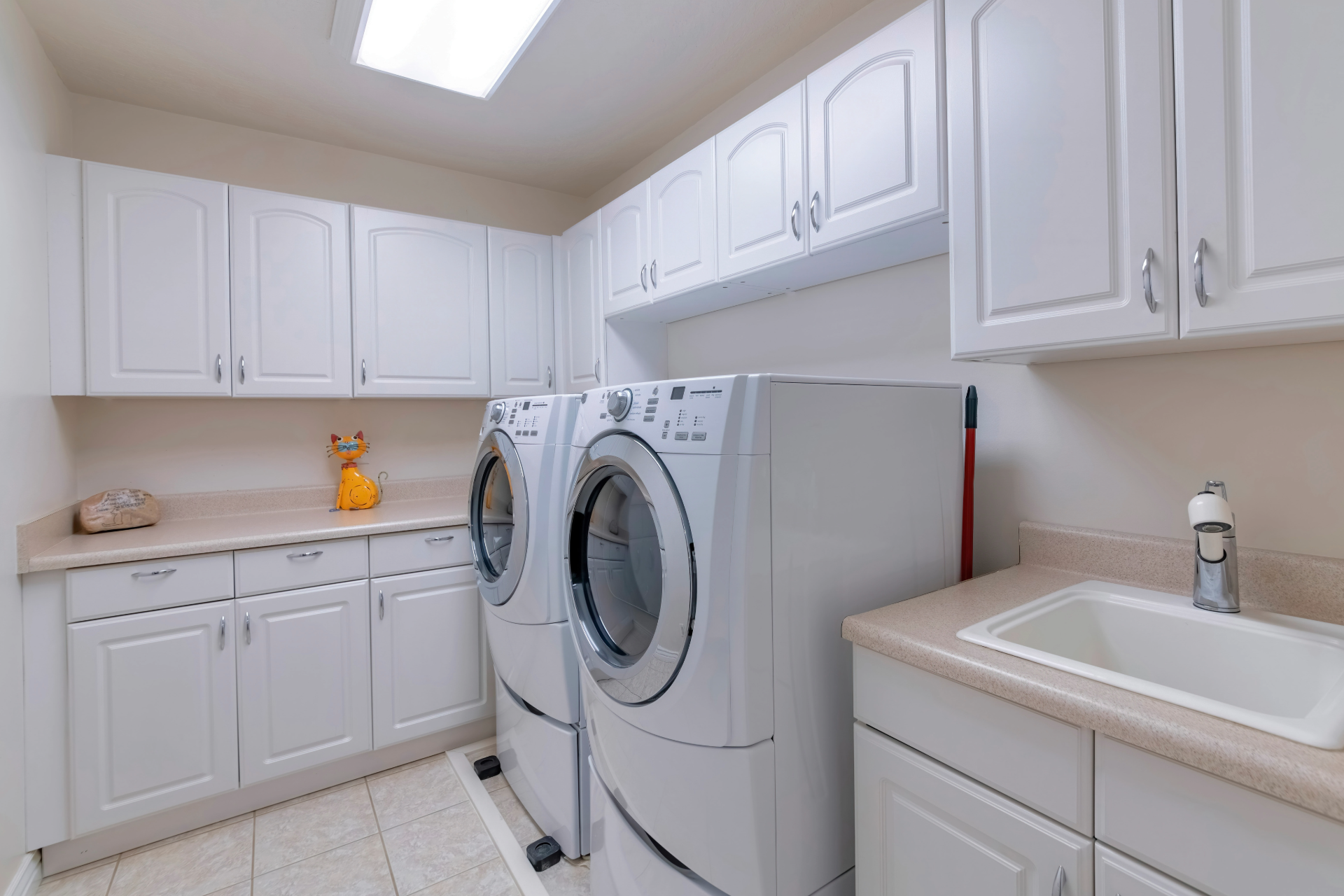 White laundry room with washer, dryer, cabinets, and a utility sink.