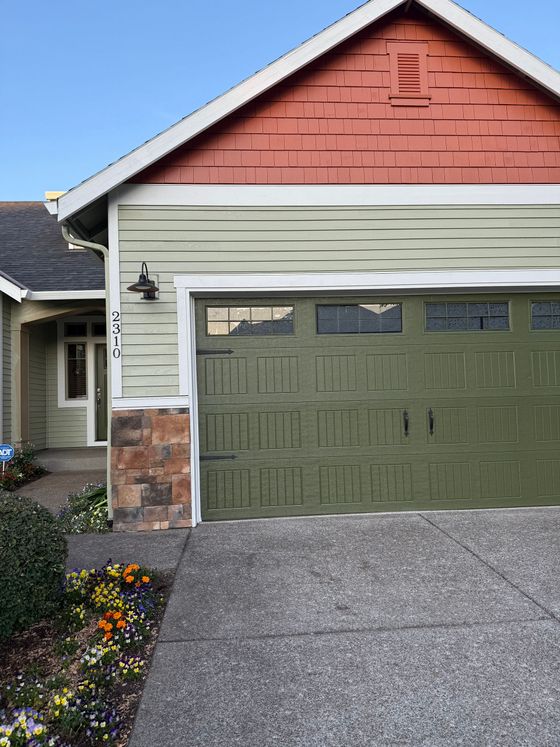 A person is painting the side of a building with a roller.