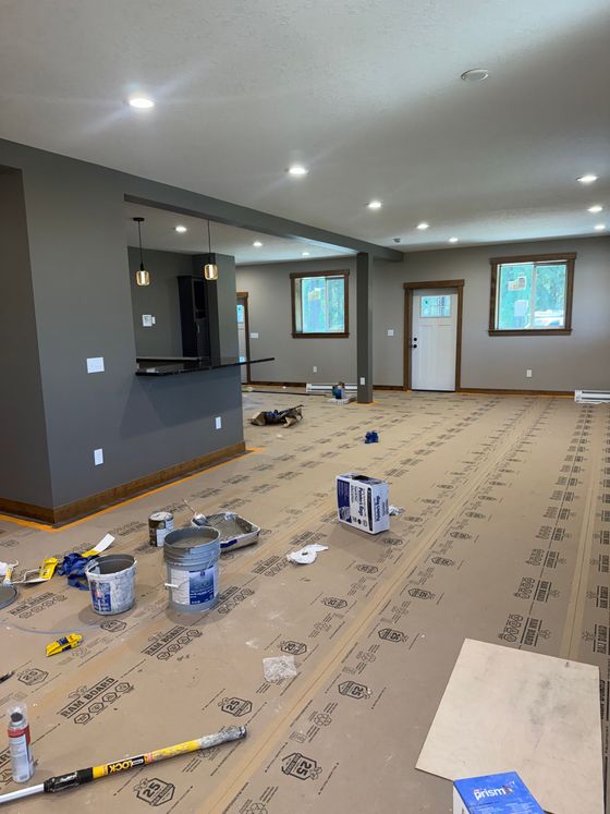 A living room with a pink chair , a table , and a vase of flowers.
