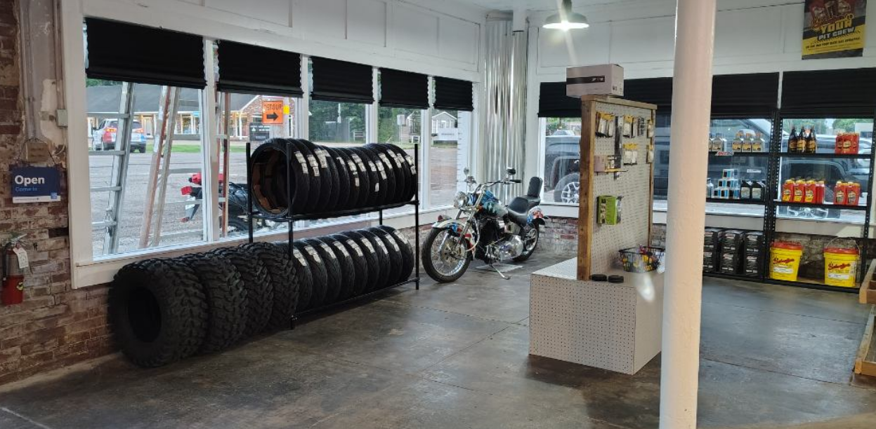 A motorcycle is parked in a garage next to a stack of tires.
