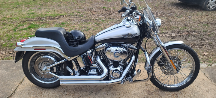 A harley davidson motorcycle is parked on the sidewalk next to a car.