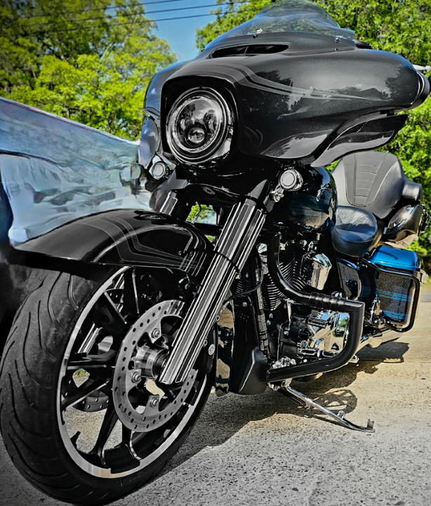 A black motorcycle is parked on the side of the road next to a car.