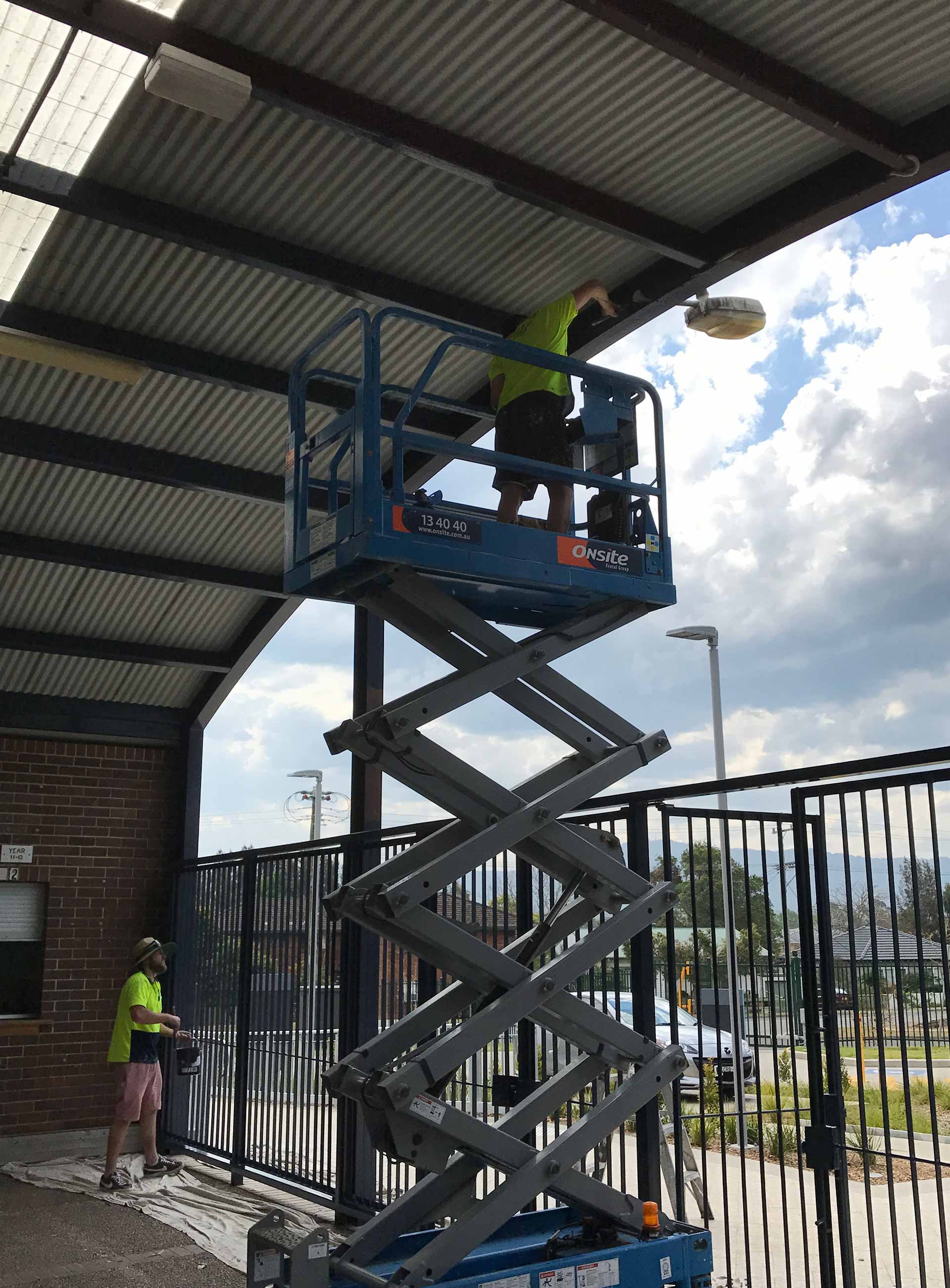 Two men painting a roof and gate