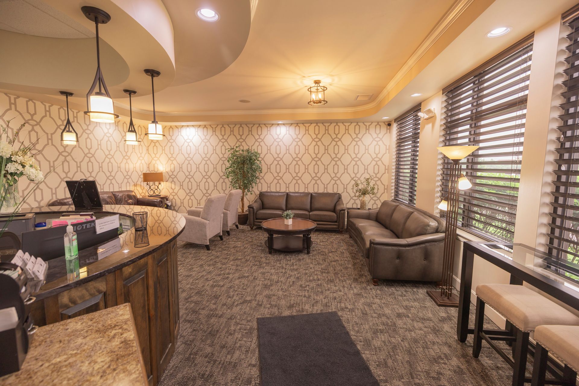 A waiting room with a couch , table , chairs and a counter.