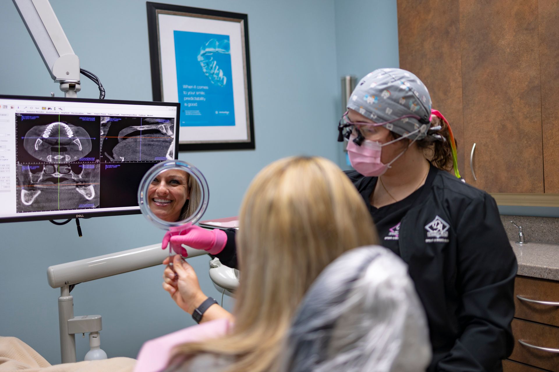 A dentist is looking at a patient 's smile in a mirror.