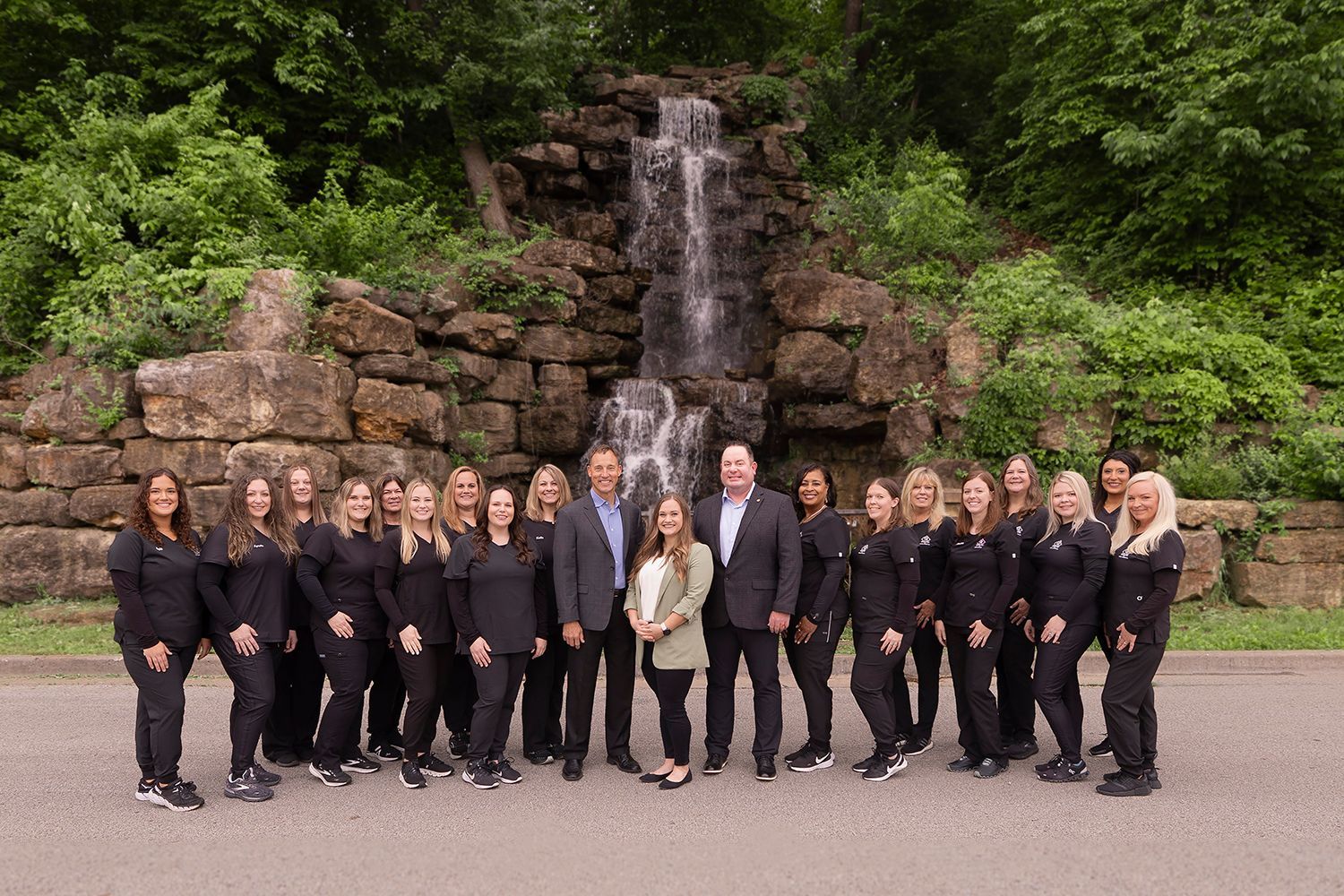 A group of people are posing for a picture in front of a waterfall.