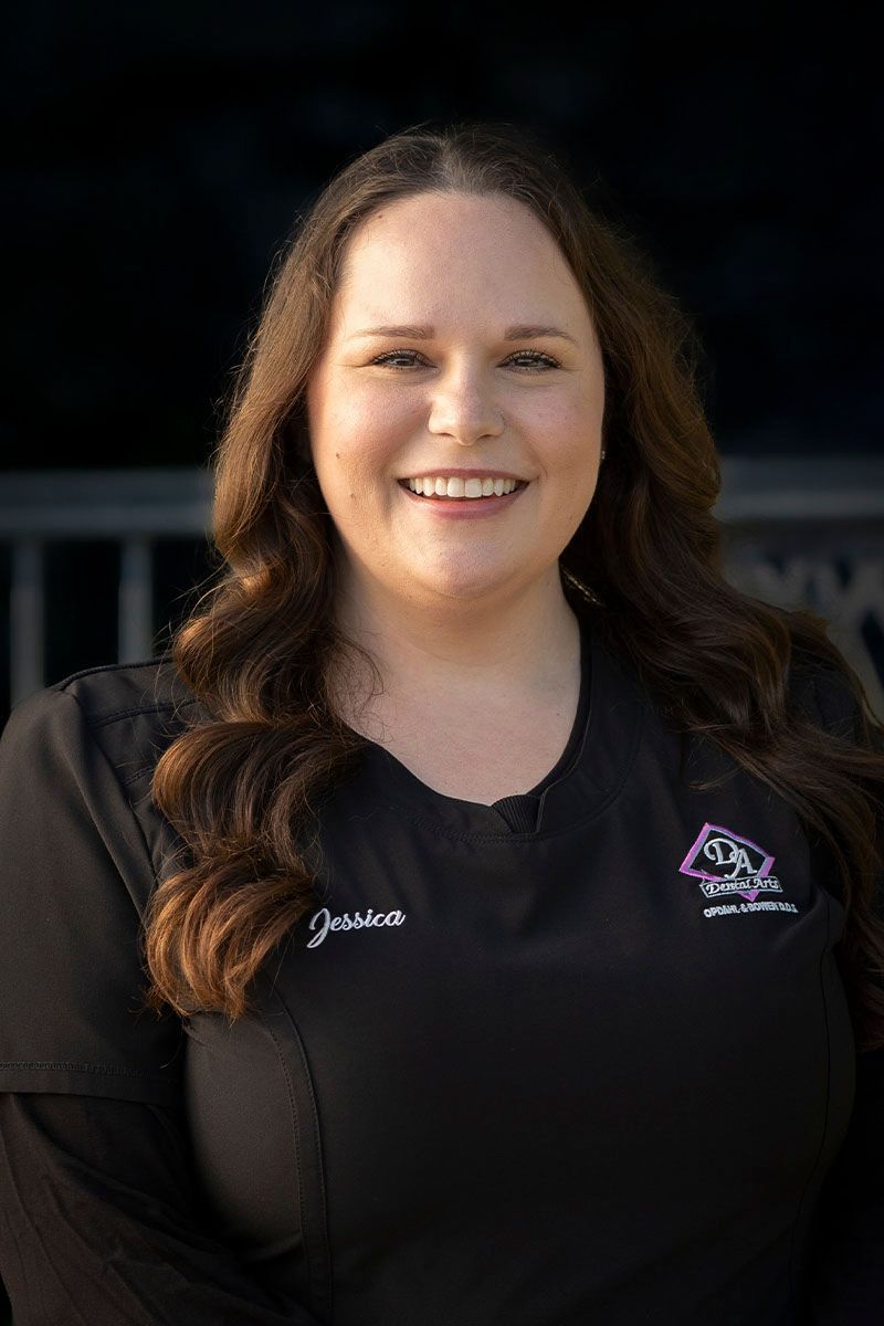 A woman in a black scrub top is smiling for the camera.
